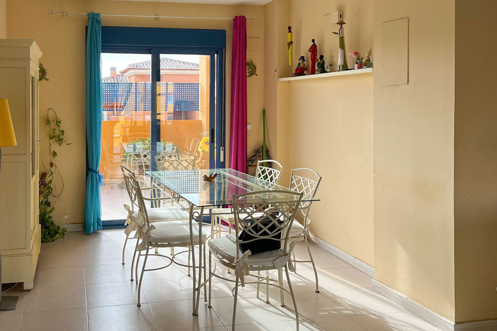 Helles Esszimmer mit Glastisch und Schmiedeeisenstühlen, Zugang zur Terrasse mit Aussicht.