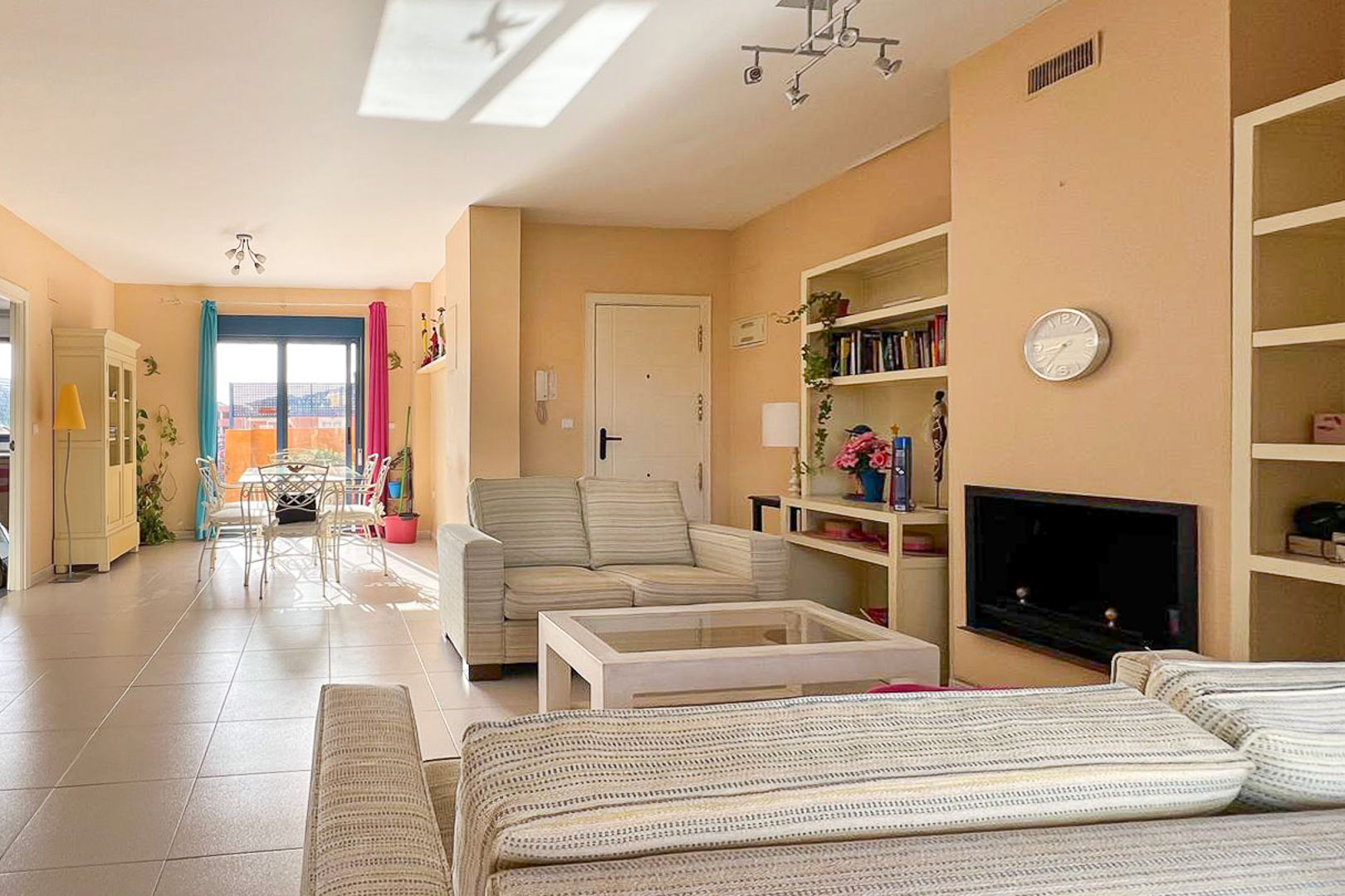 Helles Wohnzimmer mit gestreiften Sofas, Einbauregalen und Zugang zur Terrasse.