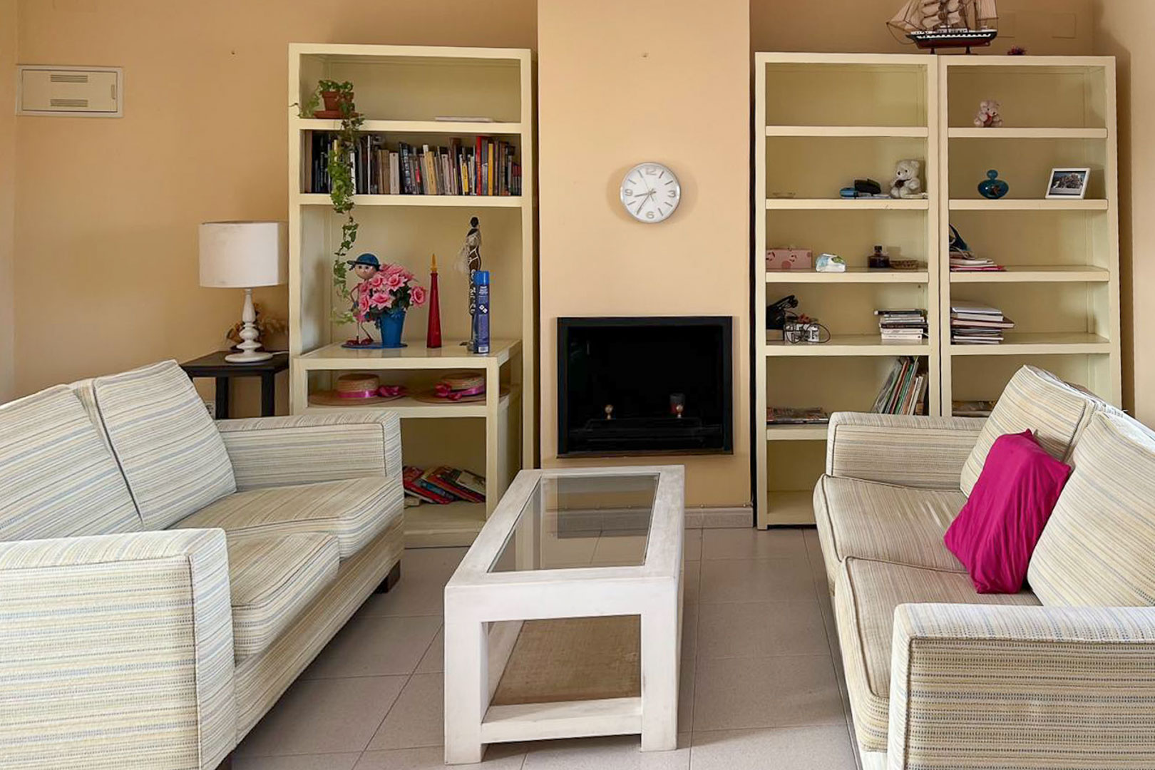 Wohnzimmer mit gestreiften Sofas, Einbauregalen und dekorativem Kamin.
