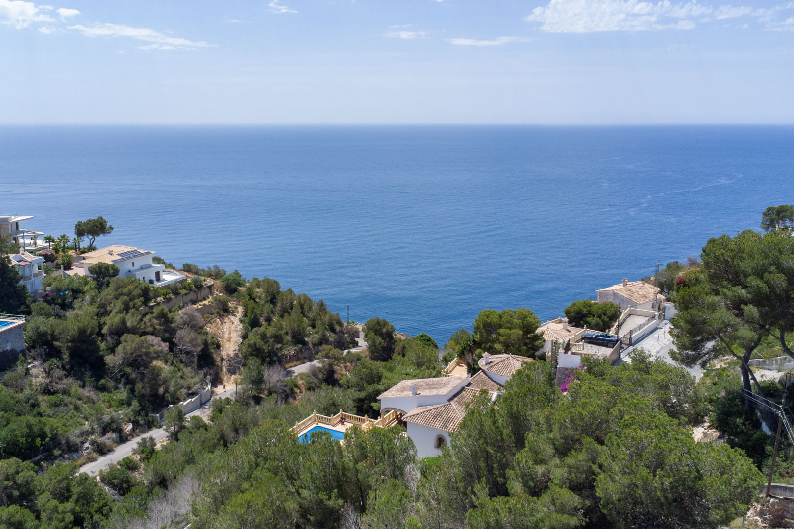 Erhöhter Panoramablick auf das Mittelmeer von Costa Nova aus, mit dichten Pinienwäldern und Villen in unmittelbarer Küstennähe von Jávea.