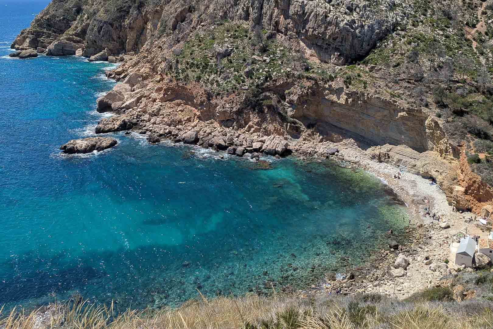 Blick auf die Cala Llebeig mit türkisfarbenem Wasser und Kalksteinklippen, erreichbar über einen Pfad nahe der Rückseite des Grundstücks.