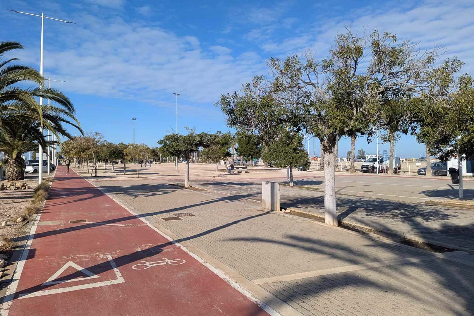 Blick auf die Fußgängerzone und den Radweg in Las Rotas, Dénia. Weitläufige, baumbestandene Bereiche entlang der Küste.