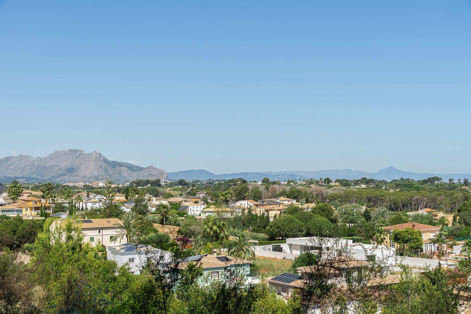 Panoramablick auf Dénia mit Häusern, Grün und Bergen im Hintergrund.