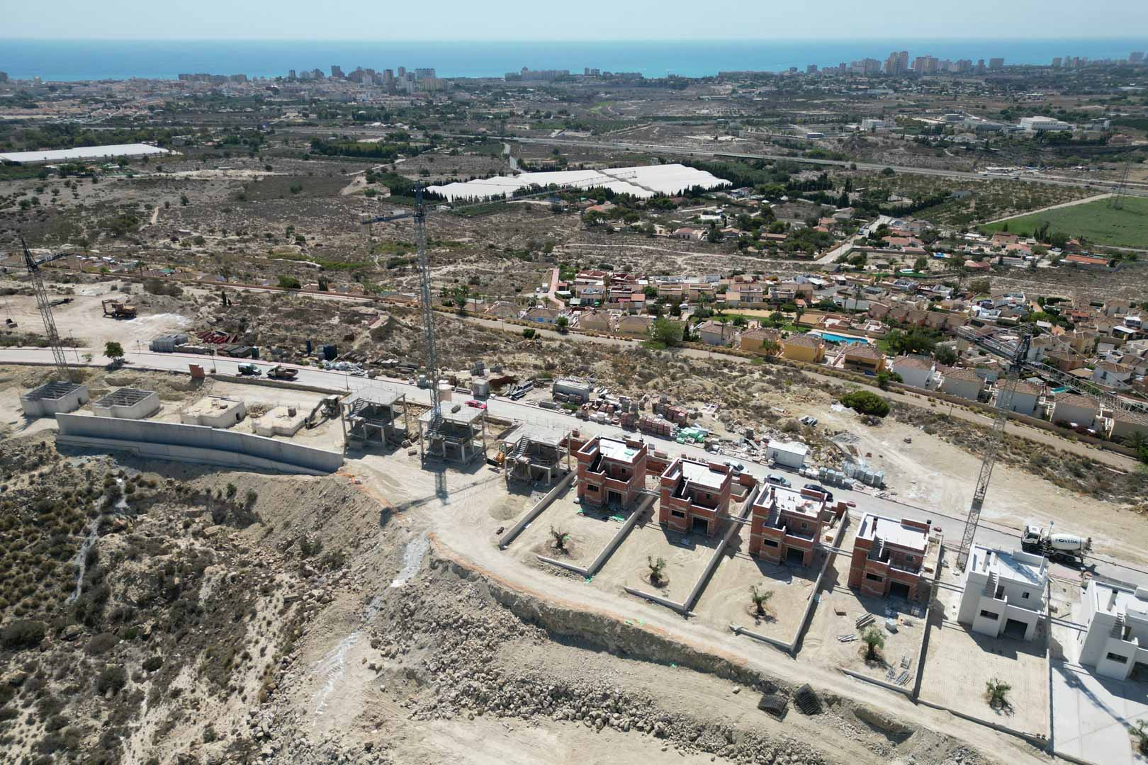 Luftaufnahme der im Bau befindlichen Villen in Hanglage mit weitem Panoramablick auf das Mittelmeer und die umliegende Küstenlandschaft.