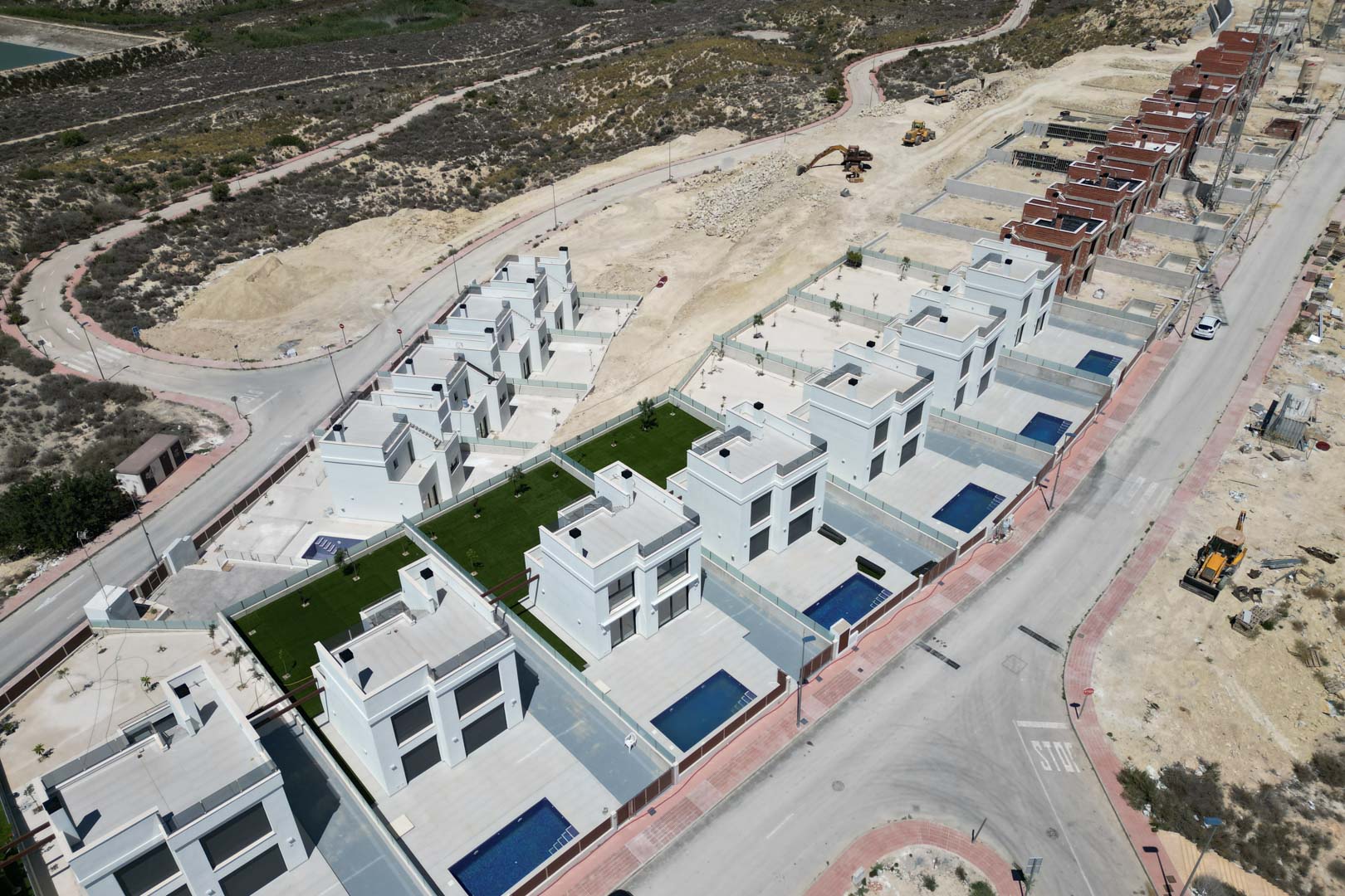 Luftbild der Wohnanlage mit weißen Villen im kubischen Design, individuellen Pools und privaten Terrassen in einer erhöhten Lage inmitten der Natur.