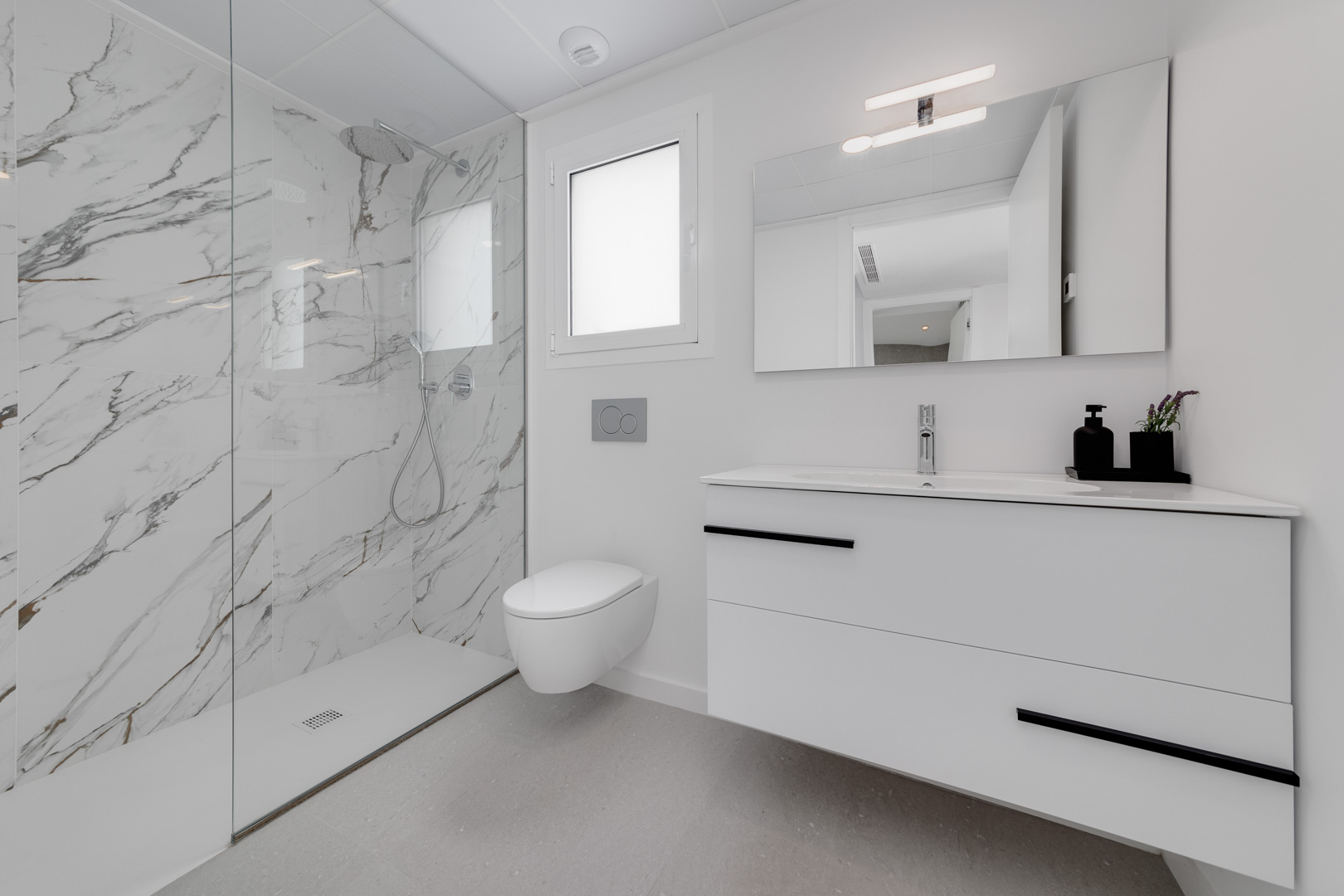 Modernes Badezimmer mit begehbarer Dusche in Marmoroptik, wandhängendem WC und schwebendem Waschtisch mit schwarzen Akzenten.