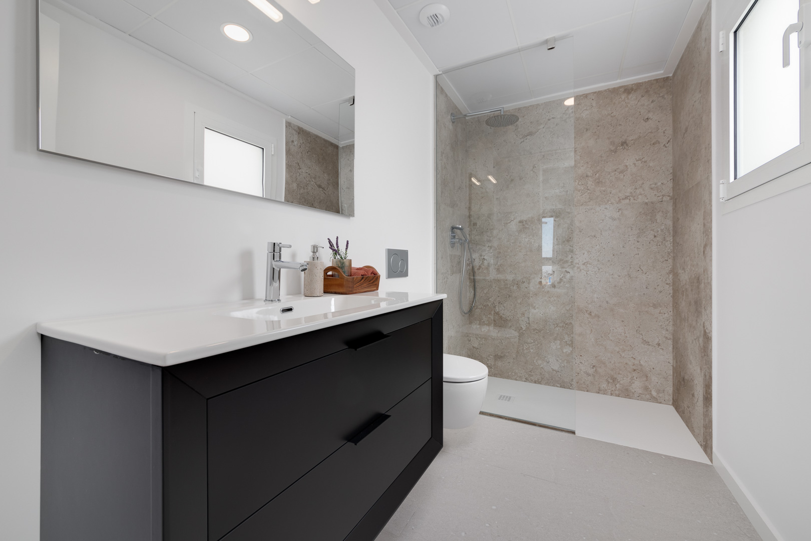 Modernes Badezimmer mit schwarzem Waschtisch, begehbarer Dusche mit Fliesen in Steinoptik und hochwertigen Chromarmaturen.