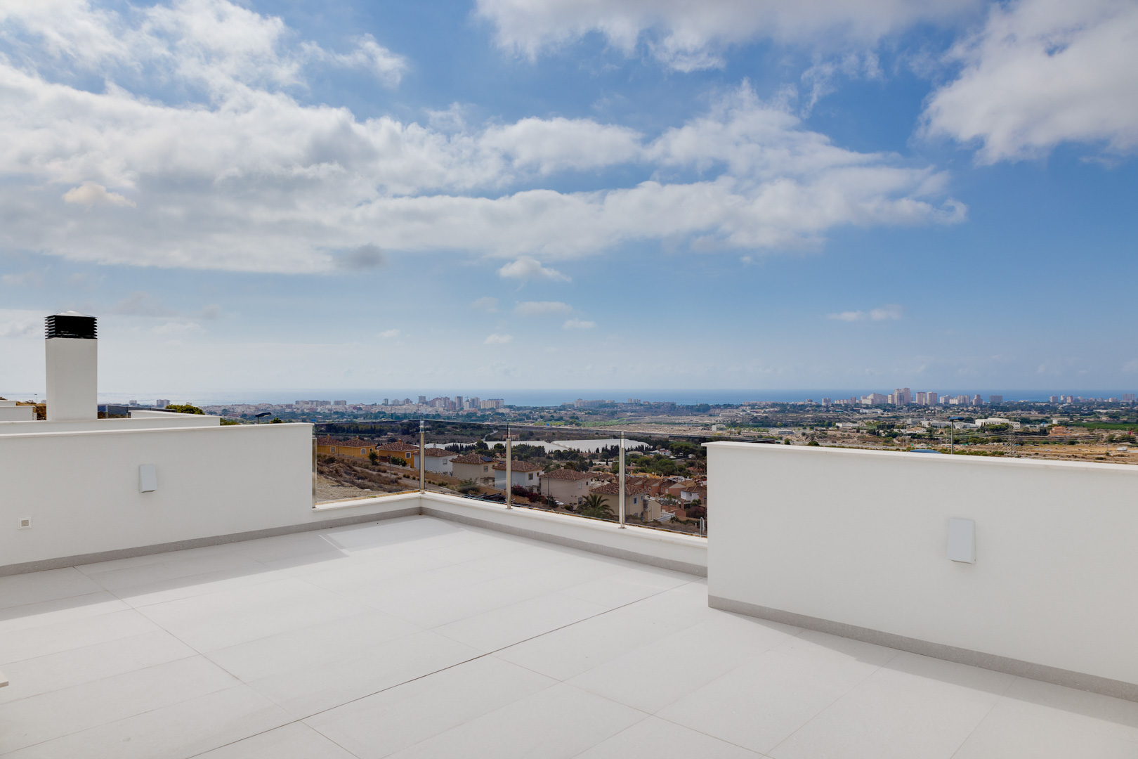 Obere Terrasse mit großformatigen Feinsteinzeugfliesen, Glasgeländern und weitem Panoramablick auf die Küste und das Mittelmeer.