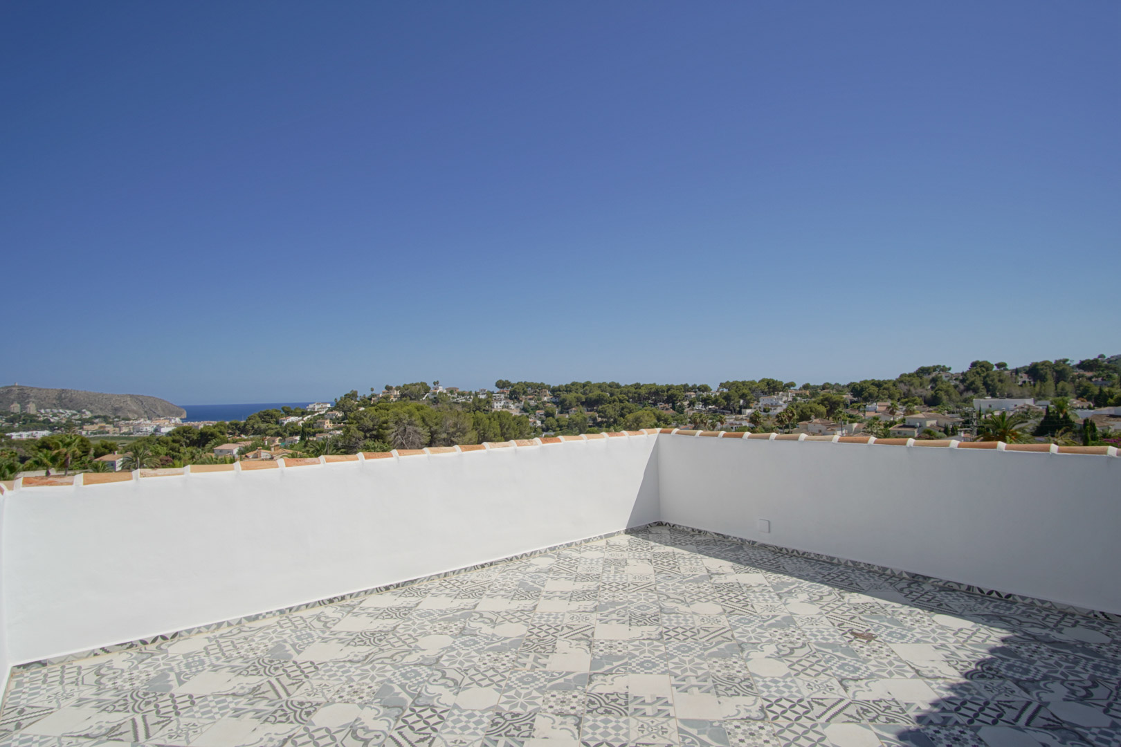 Dachterrasse mit gemusterten Keramikfliesen und Panoramablick auf das Mittelmeer, die Küste von Moraira und die umliegende Hügellandschaft.