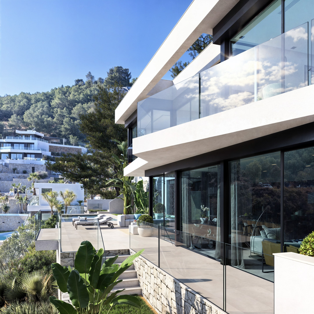Außenansicht mit weißen, auskragenden Terrassen, rahmenlosen Glasgeländern und bodentiefen Fenstern. Natursteinmauern und tropische Bepflanzung prägen den eleganten Außenbereich.