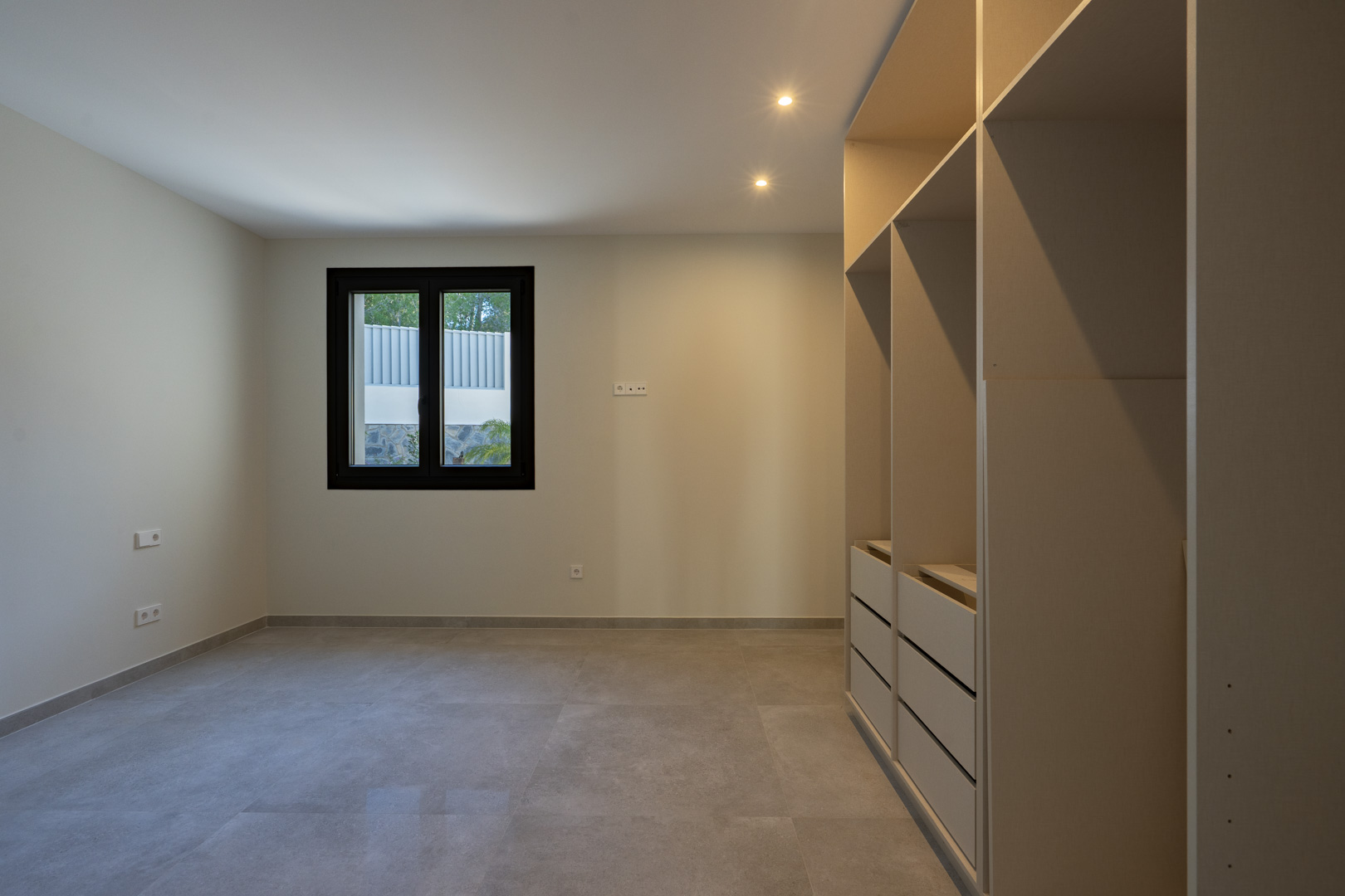 Helles Interieur mit Einbauschrank und schwarz gerahmtem Fenster.
