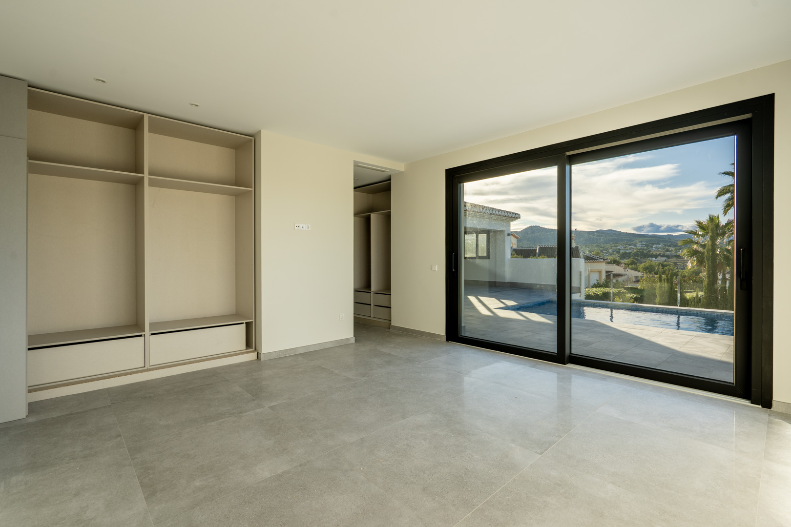 Helles Schlafzimmer mit Einbauschrank und Schiebetür zum Poolbereich.