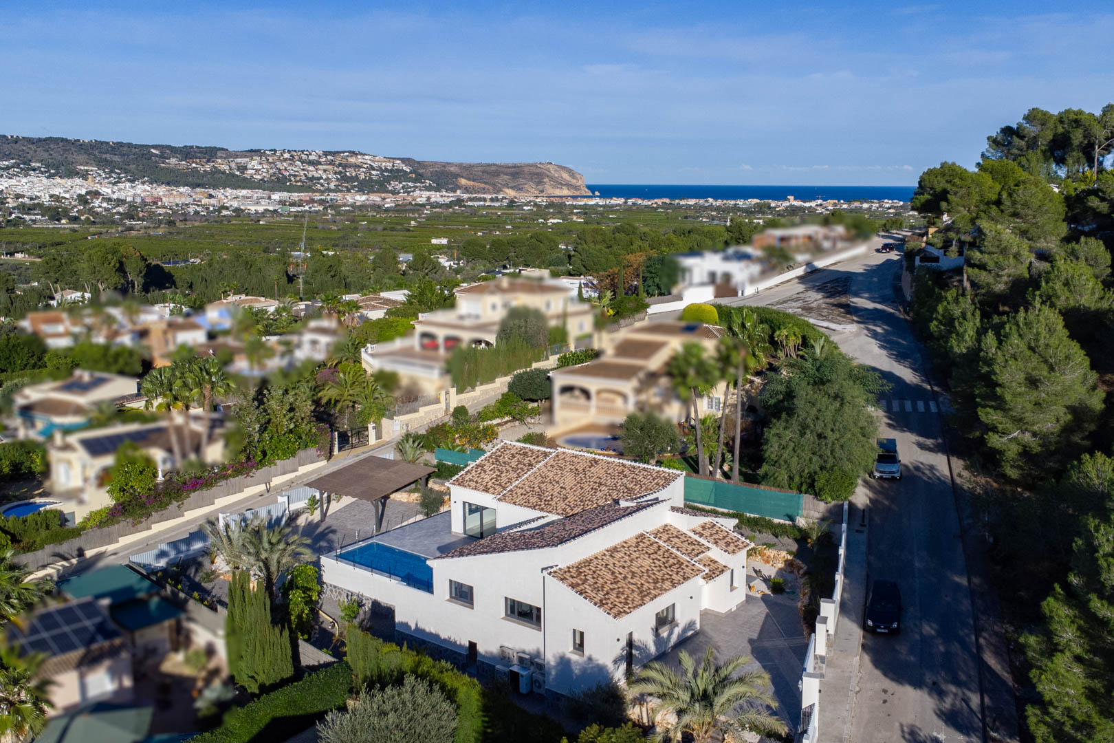 Luftaufnahme einer modernen Villa mit Pool in Jávea, umgeben von Gärten und mit Meerblick.