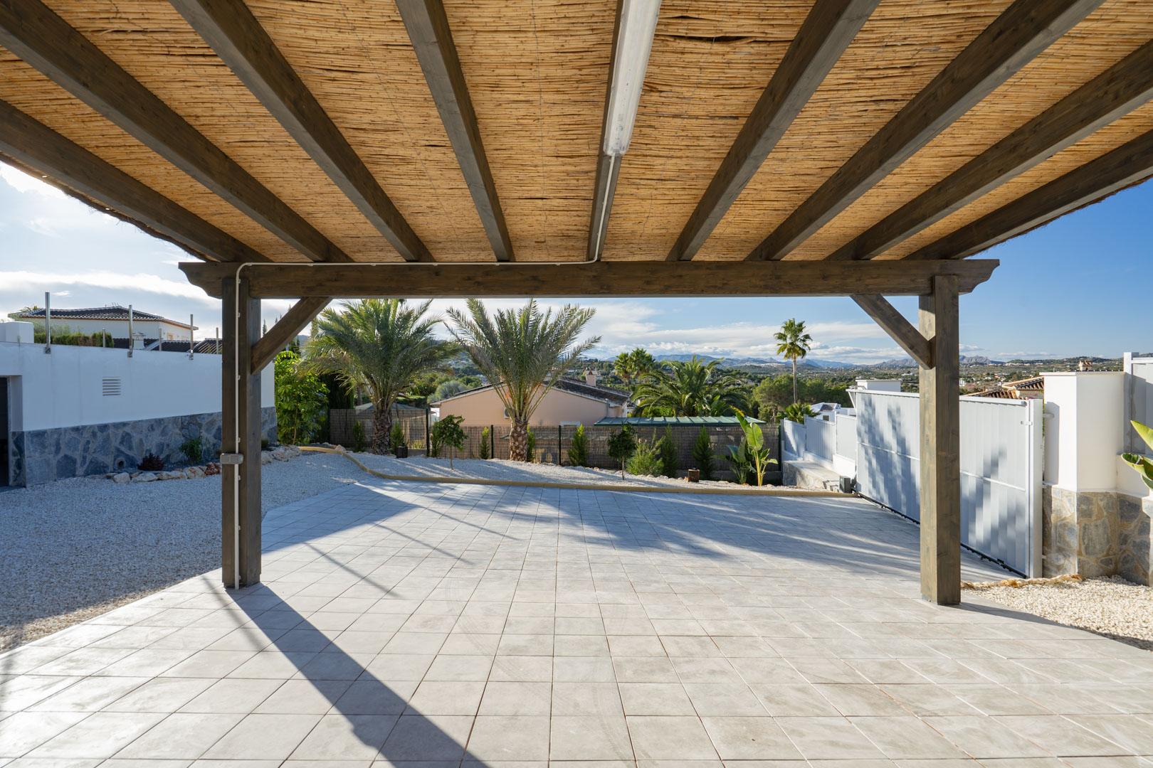 Pergola mit Holzstruktur und Schilfdeckung, über Fliesenboden in Villa in Jávea.