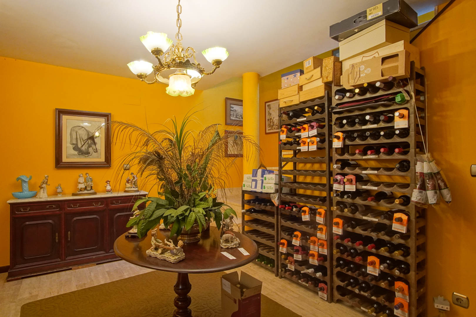 Innenliegender Weinkeller mit vertikalen Weinregalen, zentralem Holztisch und klassischem Sideboard auf Marmorboden und ockerfarbenen Wänden.