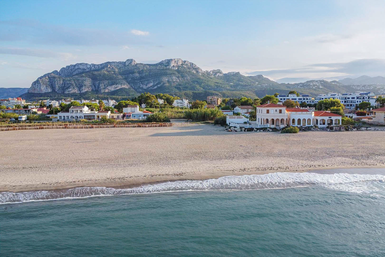 Luftaufnahme des weitläufigen Sandstrandes in El Vergel mit Blick auf das Mittelmeer und die markante Bergkette im Hintergrund.