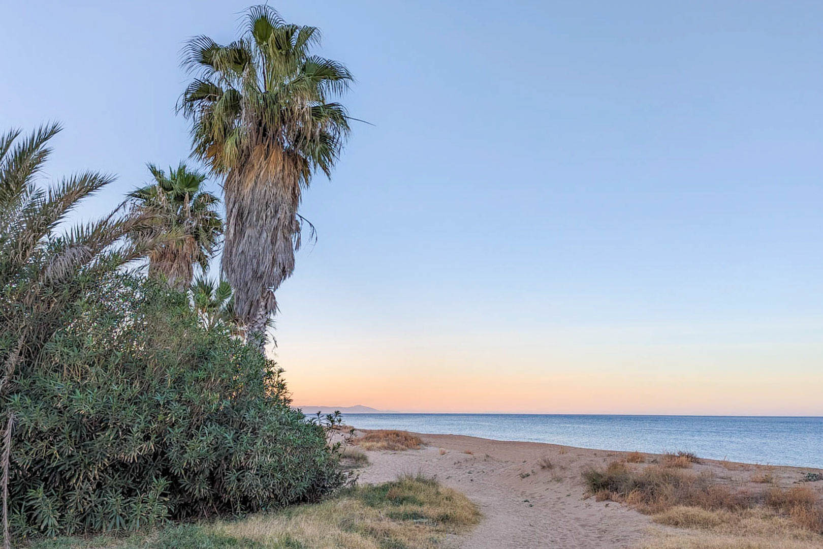 Sandstrand mit Palmen und einheimischer Vegetation in der Nähe der Villa, ideal für entspannte Stunden am Mittelmeer in der Abenddämmerung.