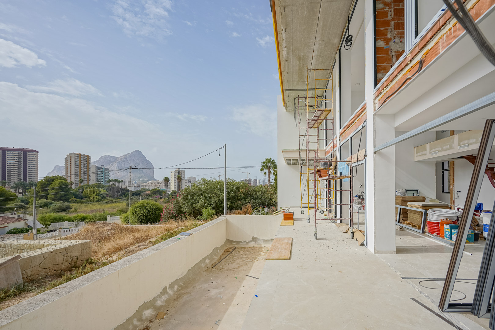 Außenansicht der im Bau befindlichen Villa mit Gerüsten, großen Fensteröffnungen und einer Terrasse mit Blick auf den Peñón de Ifach in Calpe.