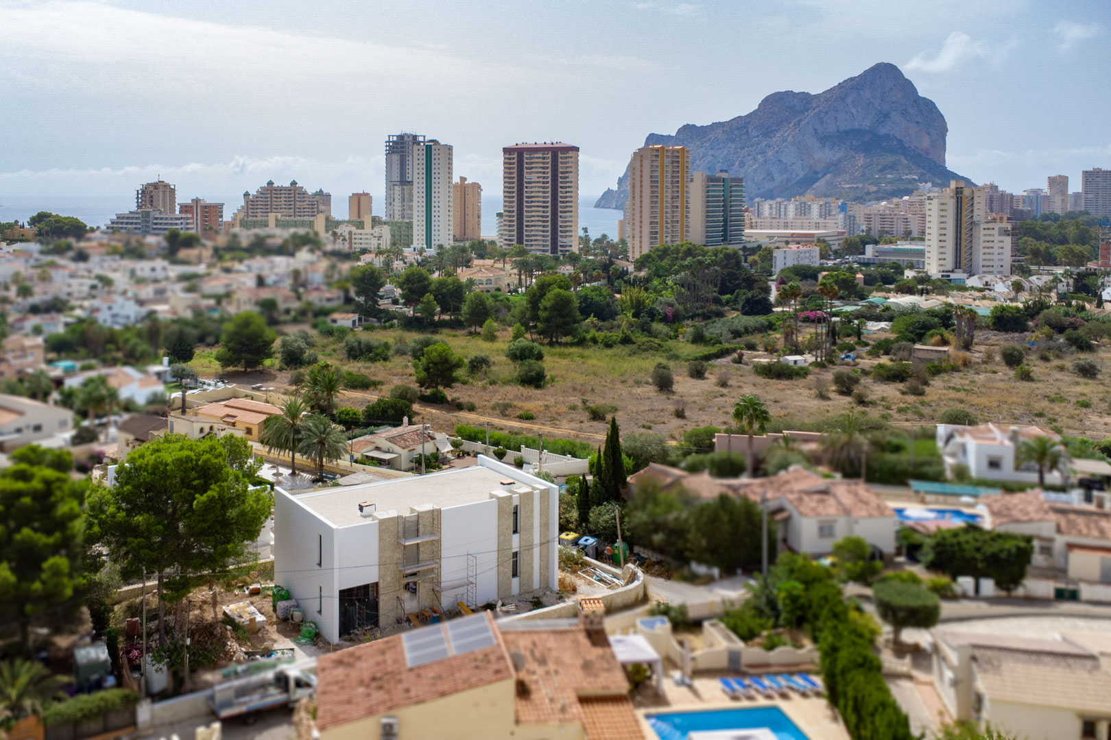 Luftansicht der Villa im Bau mit Natursteinfassade und weitem Blick auf den Peñón de Ifach sowie die Skyline von Calpe an der Costa Blanca.