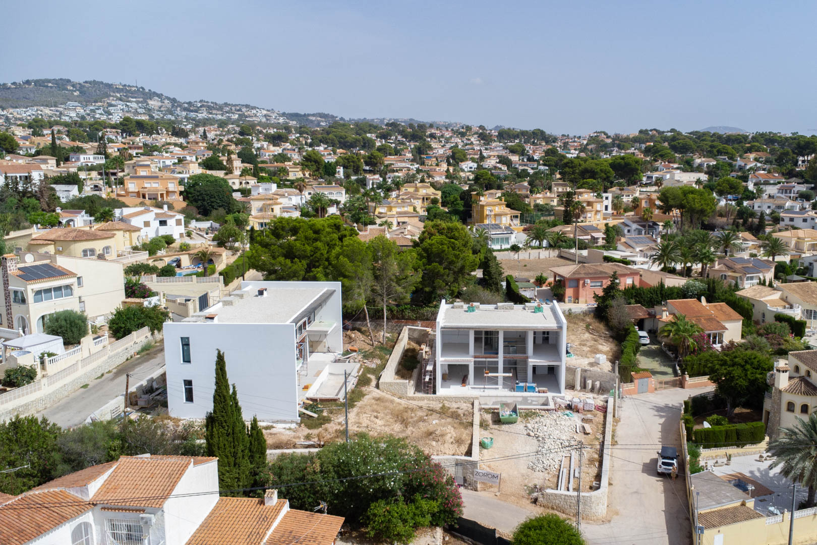Luftaufnahme der modernen zweistöckigen Villa im Bau, die die weiße Fassade und das flache Grundstück in der Wohngegend von Calpe zeigt.