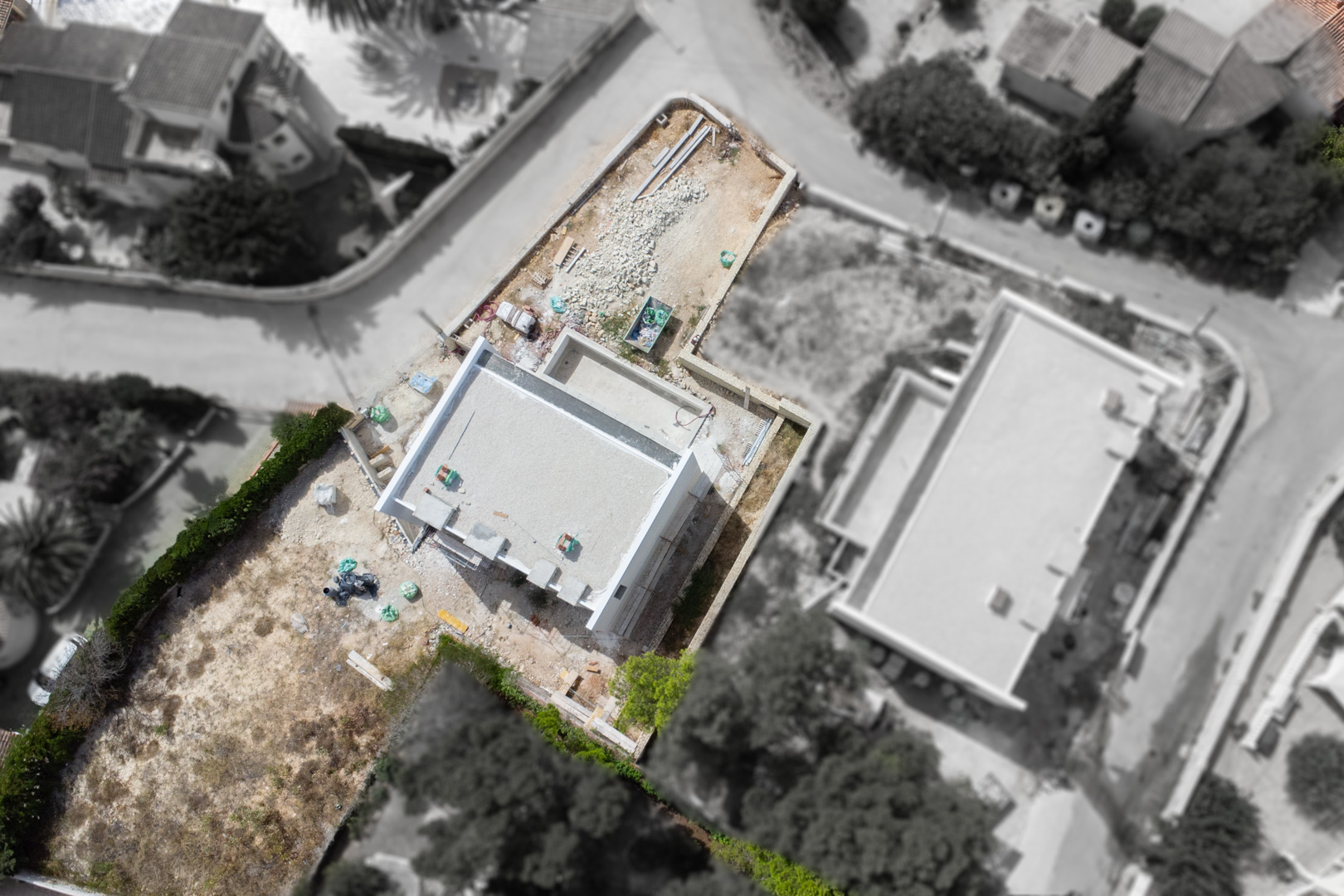 Luftaufnahme des aktuellen Baufortschritts der Villa auf dem flachen Grundstück, die den Grundriss und die Lage innerhalb des Wohngebiets zeigt.