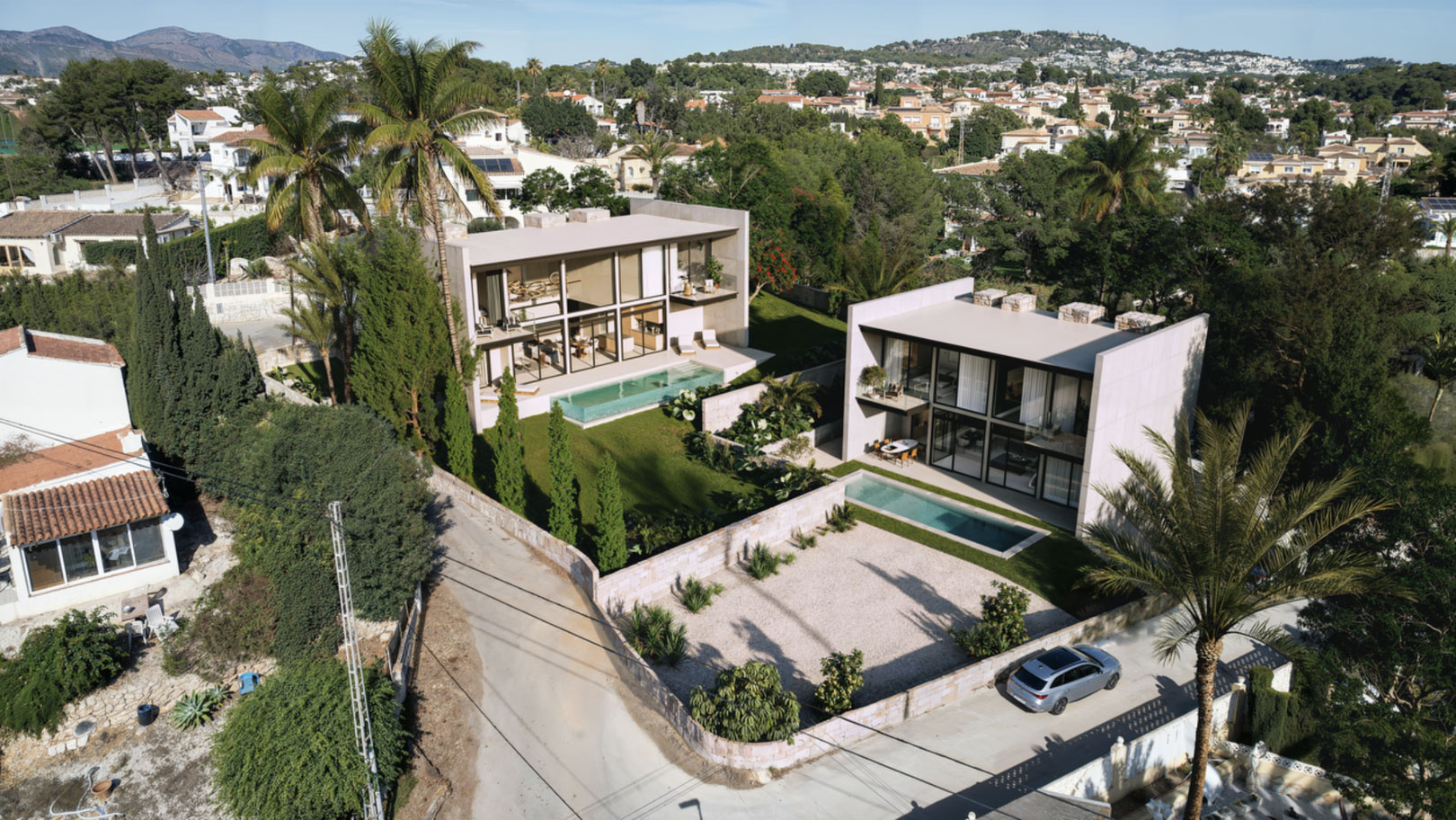 Luftaufnahme von zwei modernen Villen mit Glasfassaden, privaten Pools und mediterranen Gärten in einer ruhigen Wohngegend von Calpe.