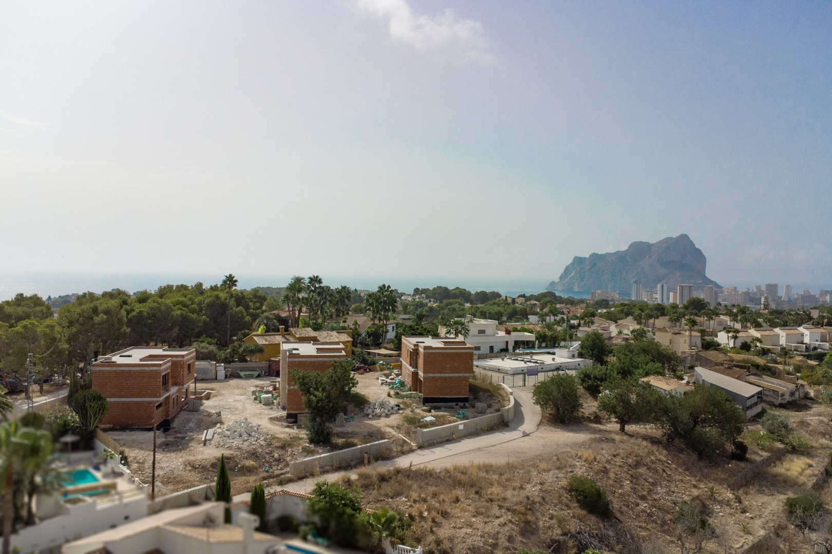Luftaufnahme der drei im Bau befindlichen Villen in Partida Gran Sol mit Blick auf den Peñón de Ifach und die Skyline von Calpe am Mittelmeer.