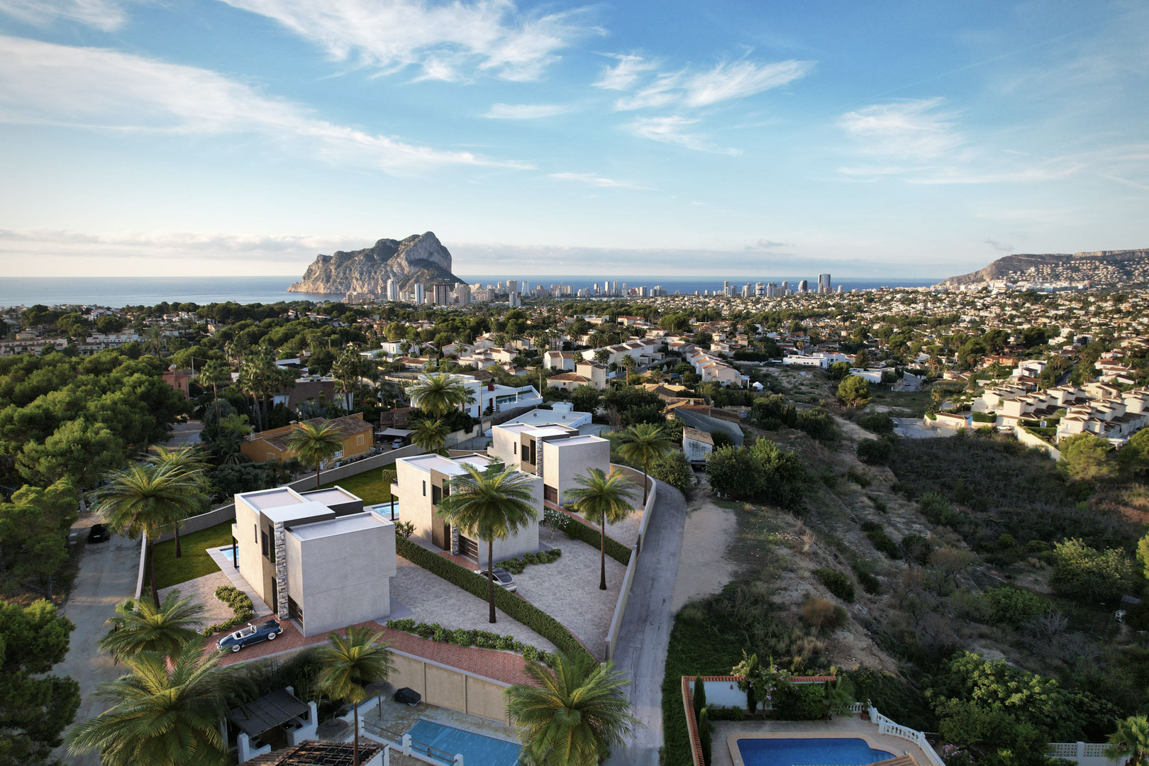Luftaufnahme von drei modernen Villen in kubischer Bauweise mit privatem Pool und Panoramablick auf den Peñón de Ifach und die Skyline von Calpe.