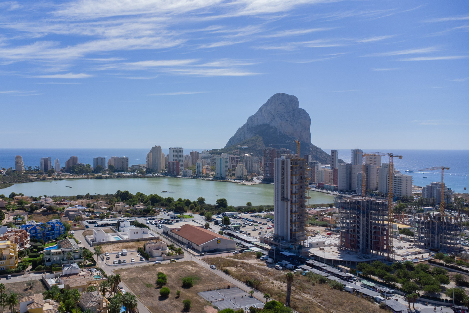 Erhöhte Panoramaaussicht auf Calpe mit dem Peñón de Ifach, der Lagune Las Salinas und der Küsten-Skyline bei klarem Himmel.