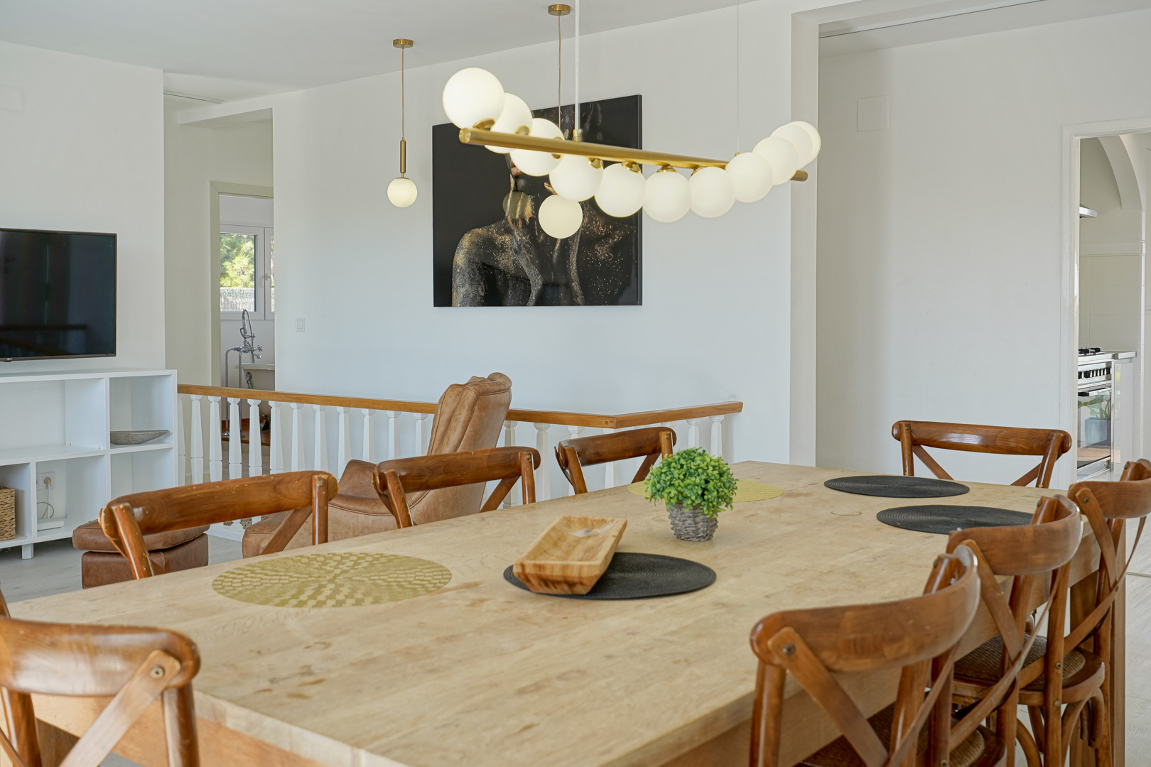 Heller Essbereich mit massivem Holztisch und modernen Kreuzlehnenstühlen, ergänzt durch eine Designer-Pendelleuchte und einen offenen Übergang zum Wohnraum.