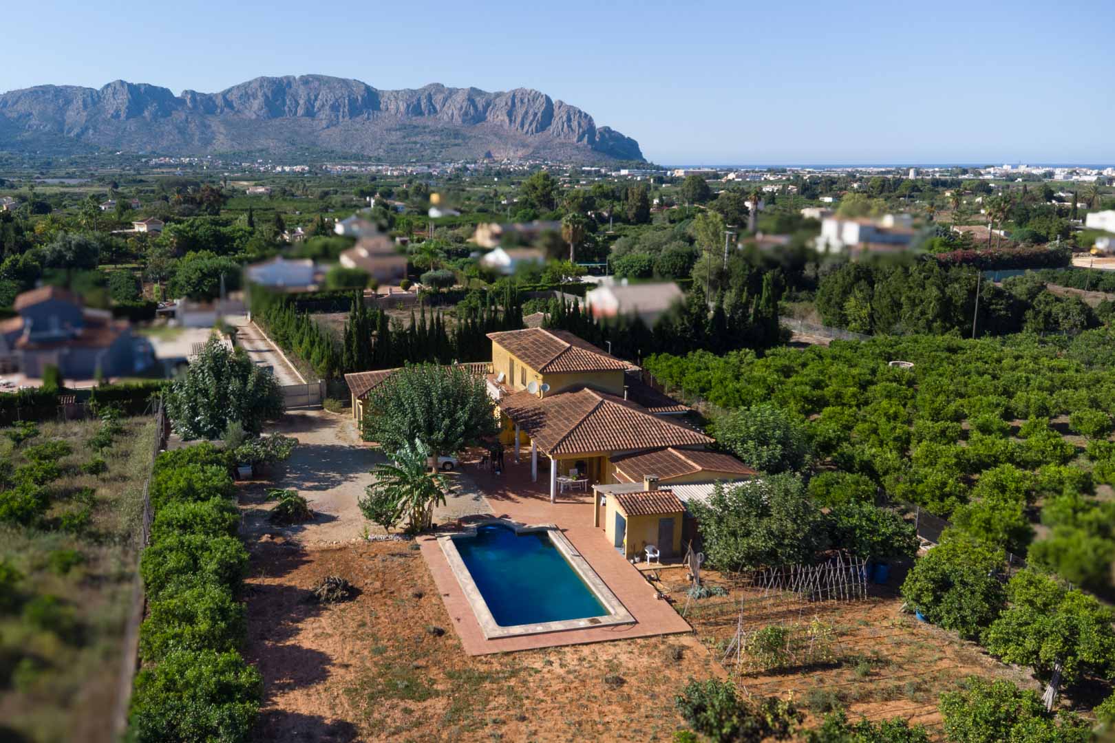 Luftaufnahme der Villa mit Terrakottadach, privatem Pool und weitläufigen Zitrusplantagen vor der Kulisse des majestätischen Segaria-Gebirges.