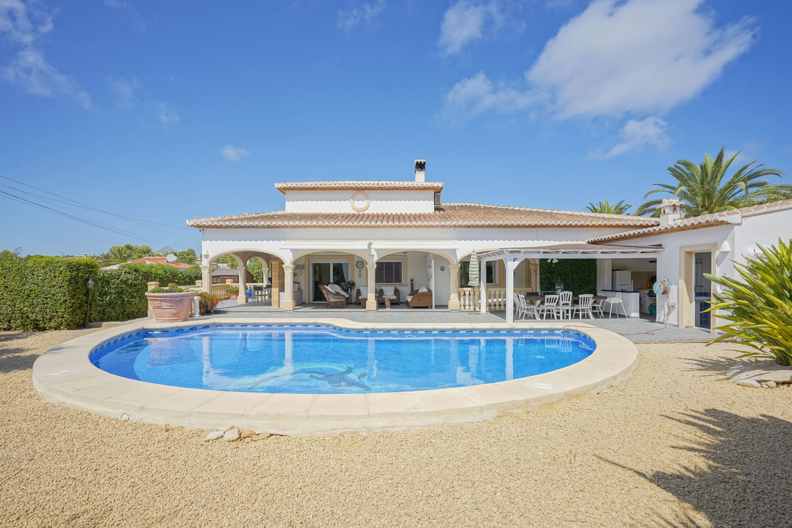 Blick auf den gefliesten Pool und die überdachte Terrasse mit Bögen einer Villa in Jávea.
