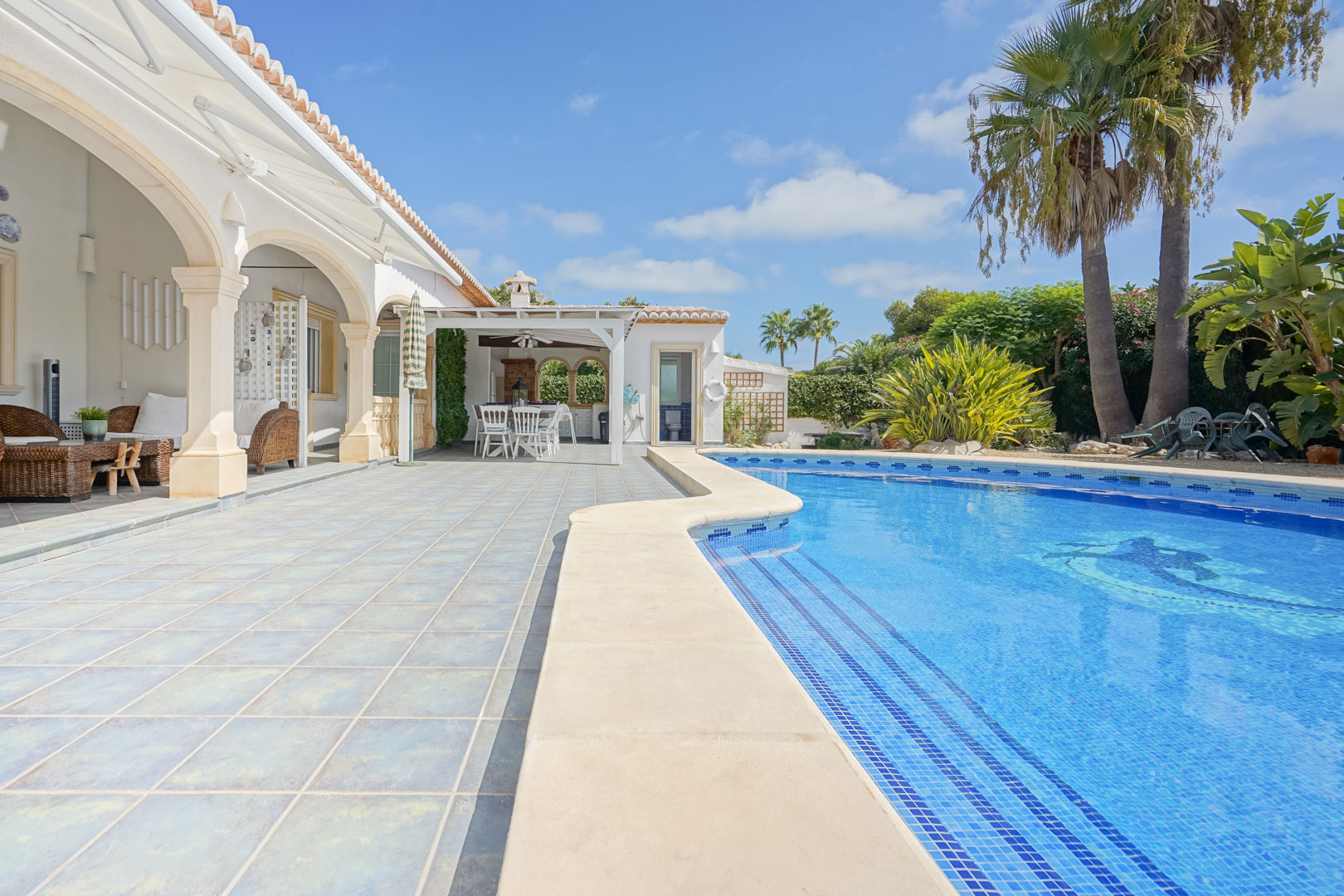 Blick auf den Pool mit blauen Fliesen und Terrasse mit Steinsäulen in Jávea.