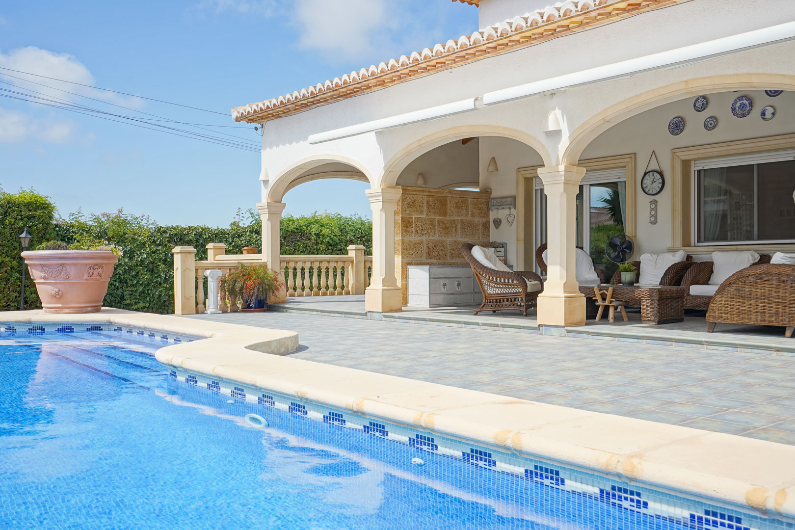 Blick auf den Pool und die überdachte Terrasse mit Bögen und Korbmöbeln in Jávea.