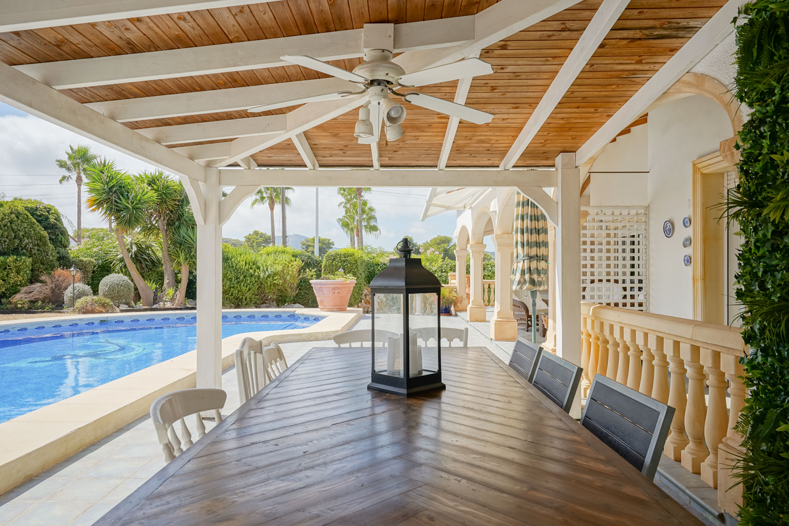 Überdachte Terrasse mit Holztisch, Blick auf Pool und Garten in Jávea.