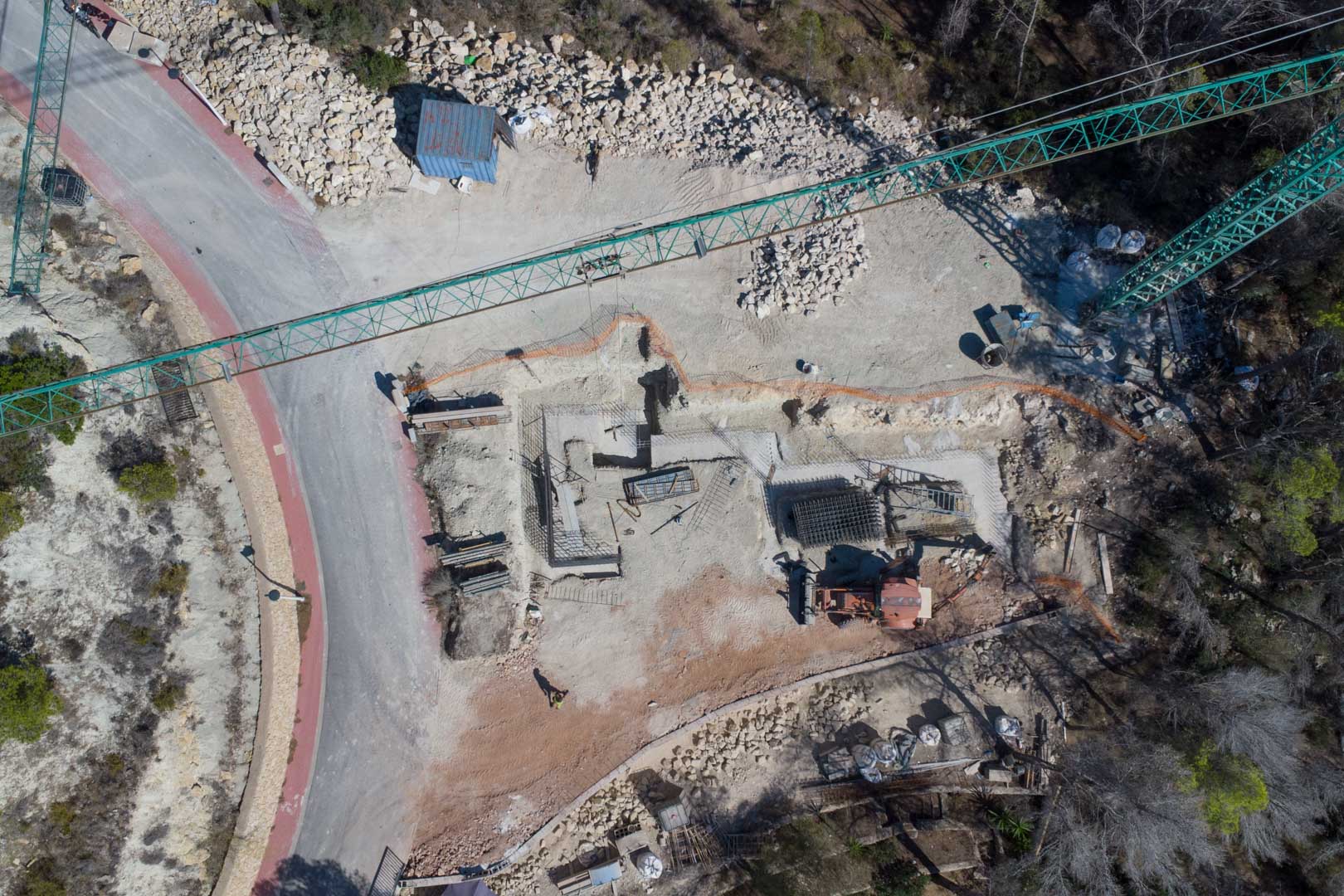 Luftaufnahme der ersten Bauphase mit Fundamenten, Stahlbewehrungen und einem Baukran auf dem Grundstück in Moraira.