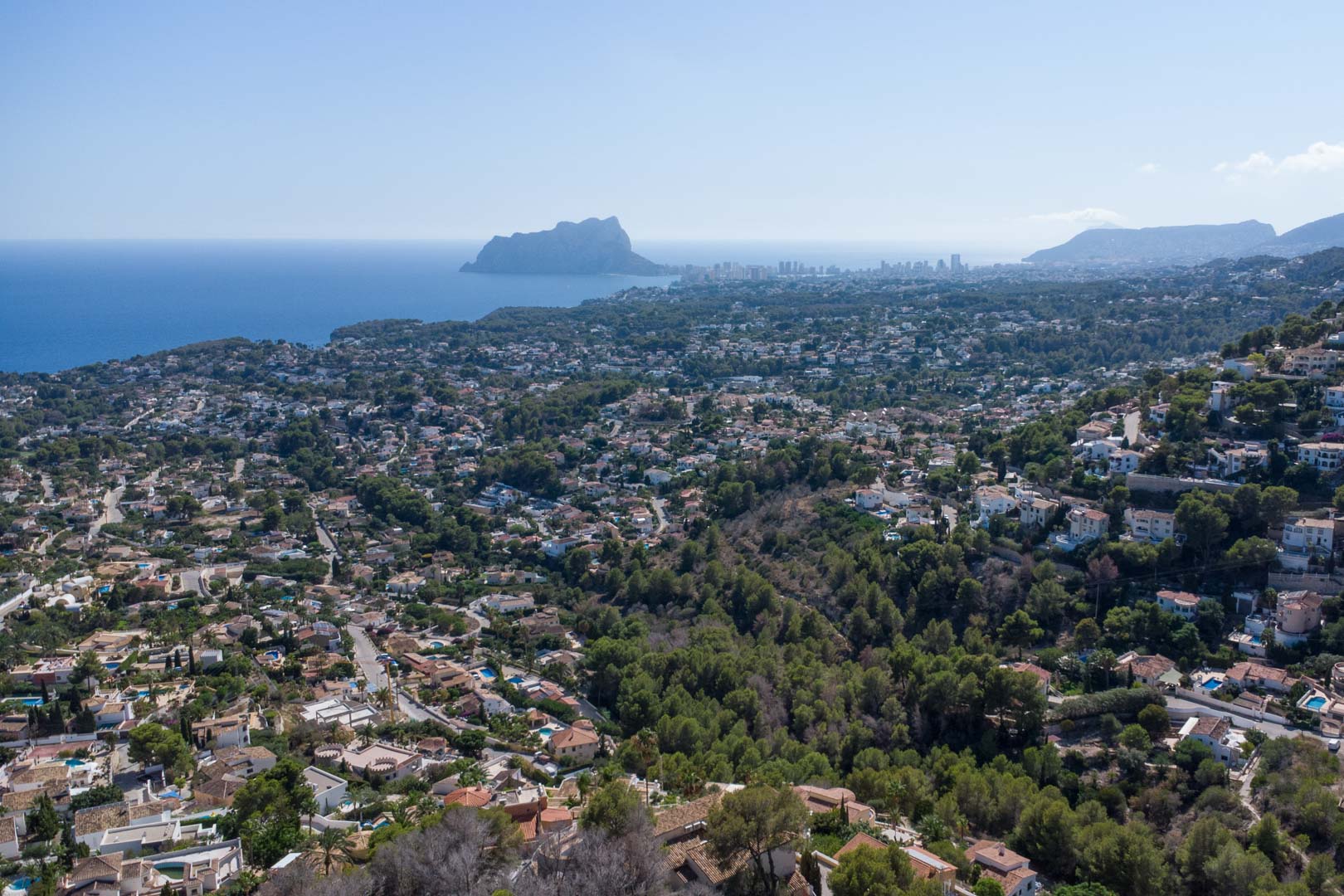 Panoramische Luftaufnahme der Küste von Moraira und Calpe mit dem markanten Peñón de Ifach und bewaldeten Wohnhügeln am Mittelmeer.