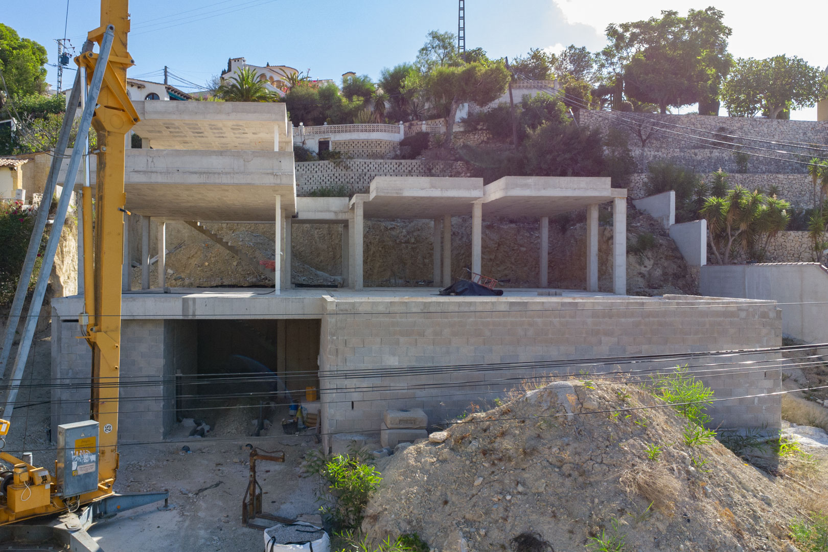 Außenansicht des Stahlbeton-Rohbaus in San Jaime. Zu sehen sind die drei Ebenen der Villa und der Garagenbereich auf dem terrassierten Hanggrundstück.