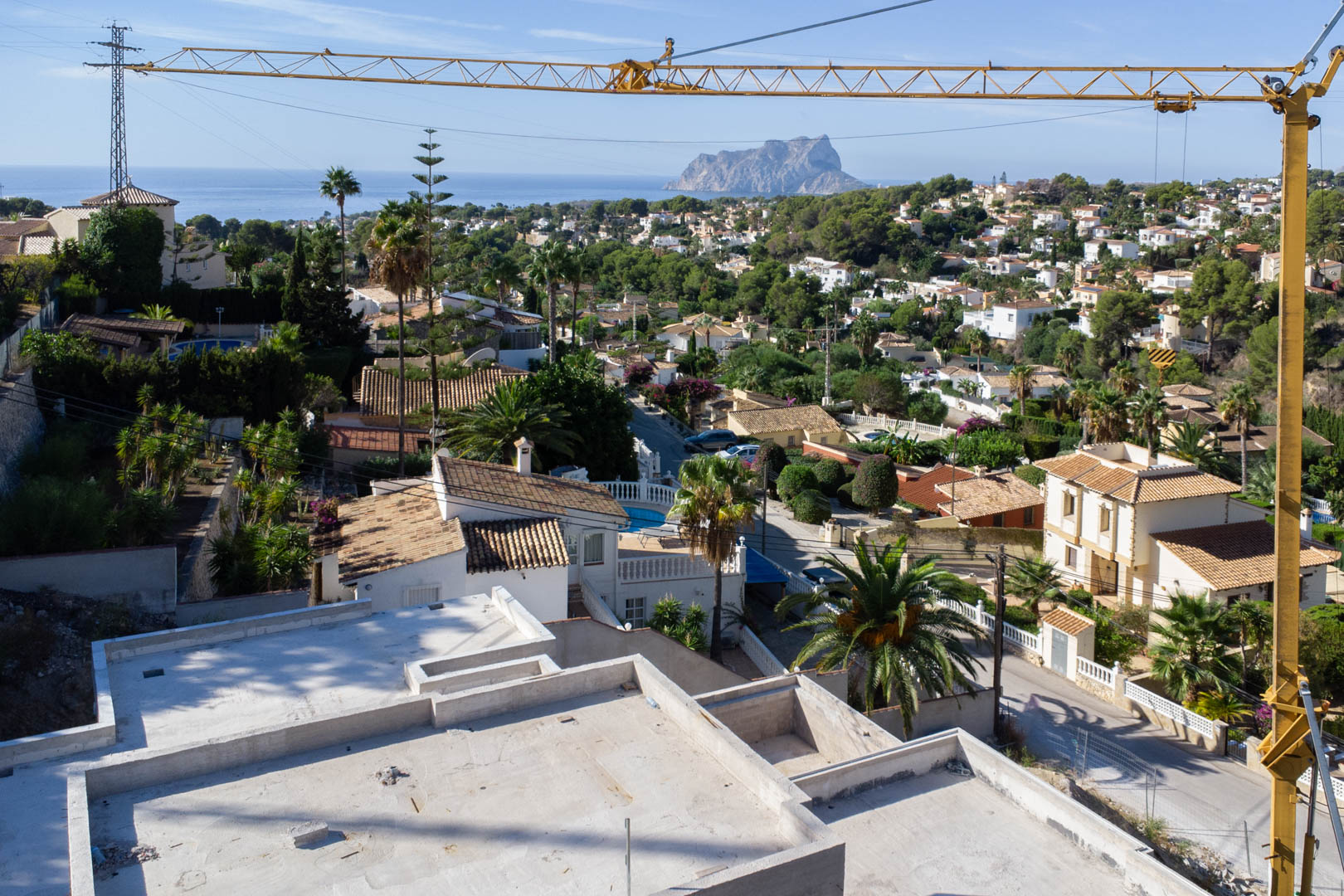 Panoramablick von der oberen Ebene des Rohbaus in San Jaime über die Wohngegend auf das Mittelmeer und den markanten Felsen Peñón de Ifach in Calpe.