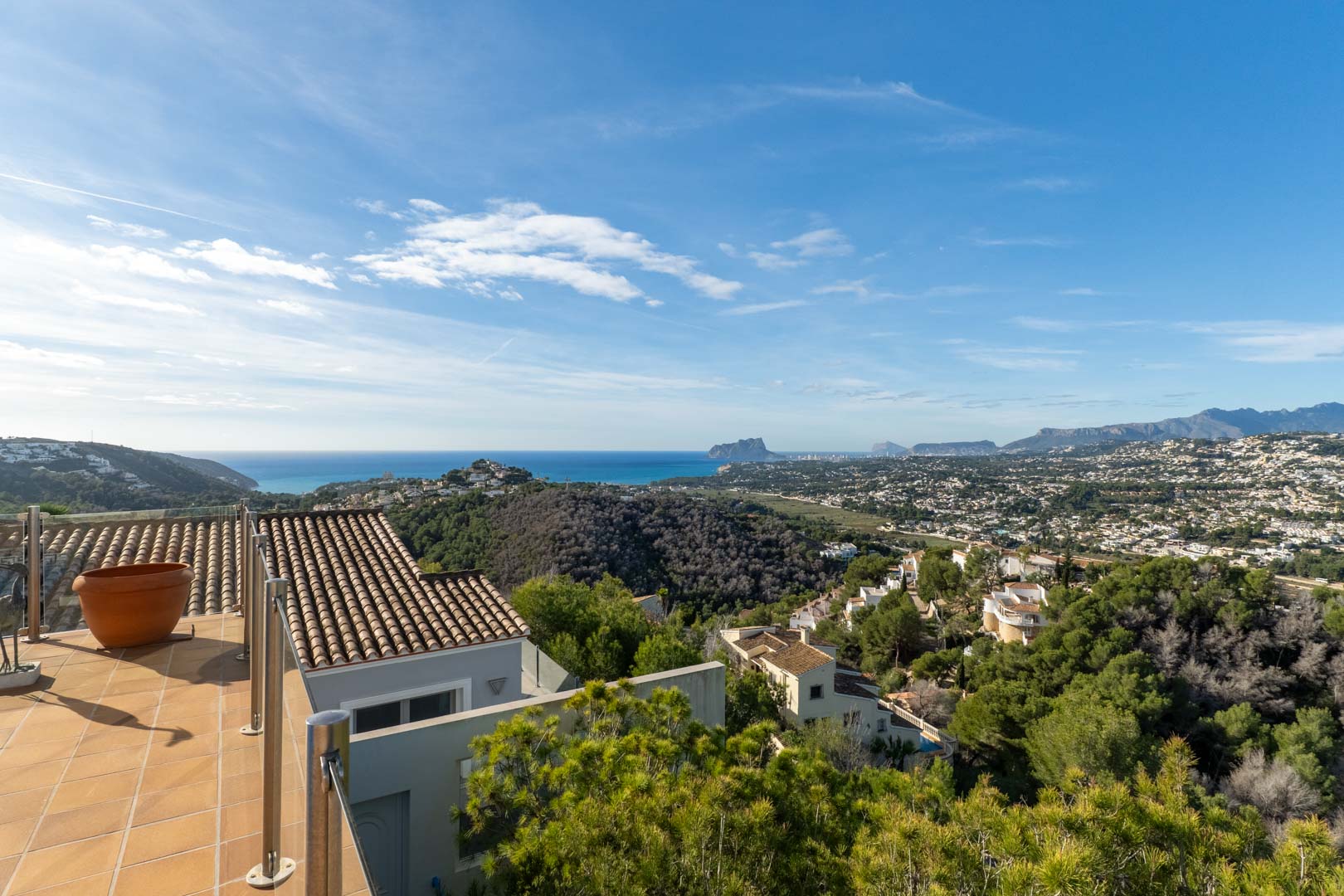 Geflieste Terrasse mit Edelstahlgeländer und weitem Panoramablick auf das Mittelmeer, den Peñón de Ifach und die umliegende Berglandschaft von Moraira.