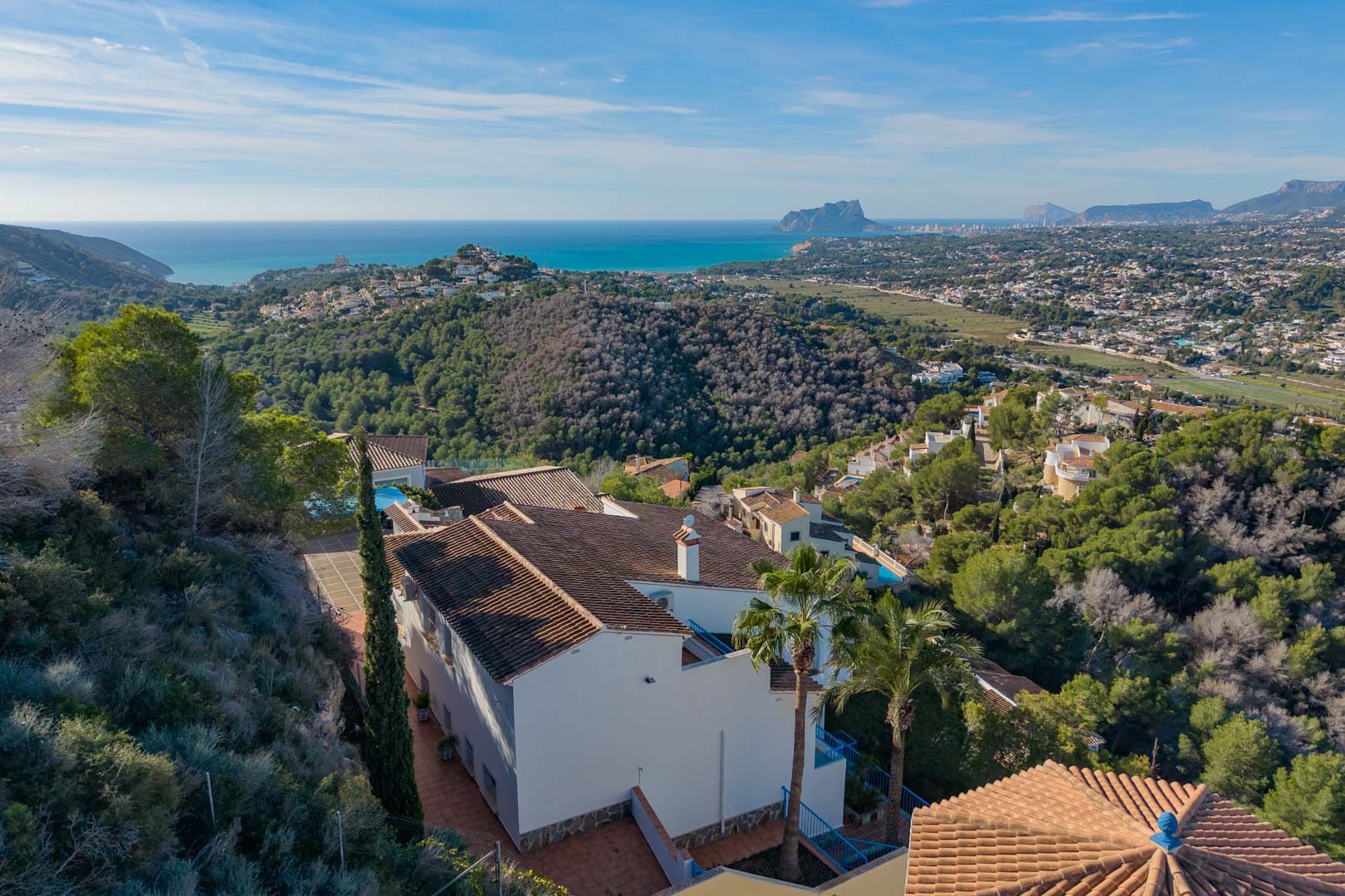 Luftaufnahme der Villa mit mediterranem Ziegeldach, eingebettet in Pinienwälder mit weitem Blick auf die Küste und den markanten Peñón de Ifach.