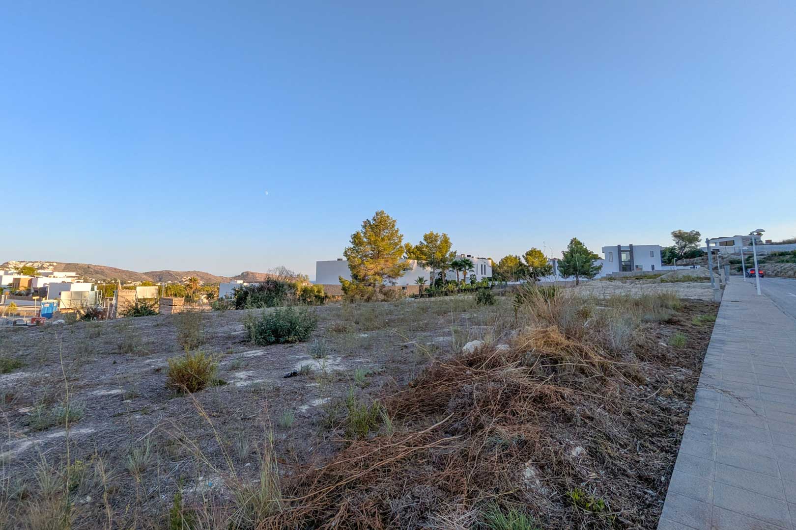 Ebenes Baugrundstück in El Tesoro, Moraira, mit freiem Talblick. Umgeben von moderner Architektur und erschlossen durch einen gepflasterten Gehweg.