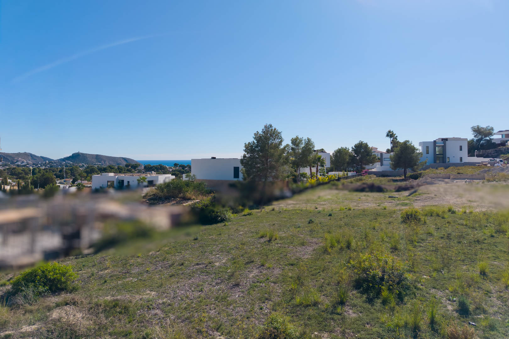 Ebenes Stadtgrundstück in El Tesoro, Moraira, mit offenem Talblick und seitlicher Meersicht, umgeben von modernen Design-Villen.