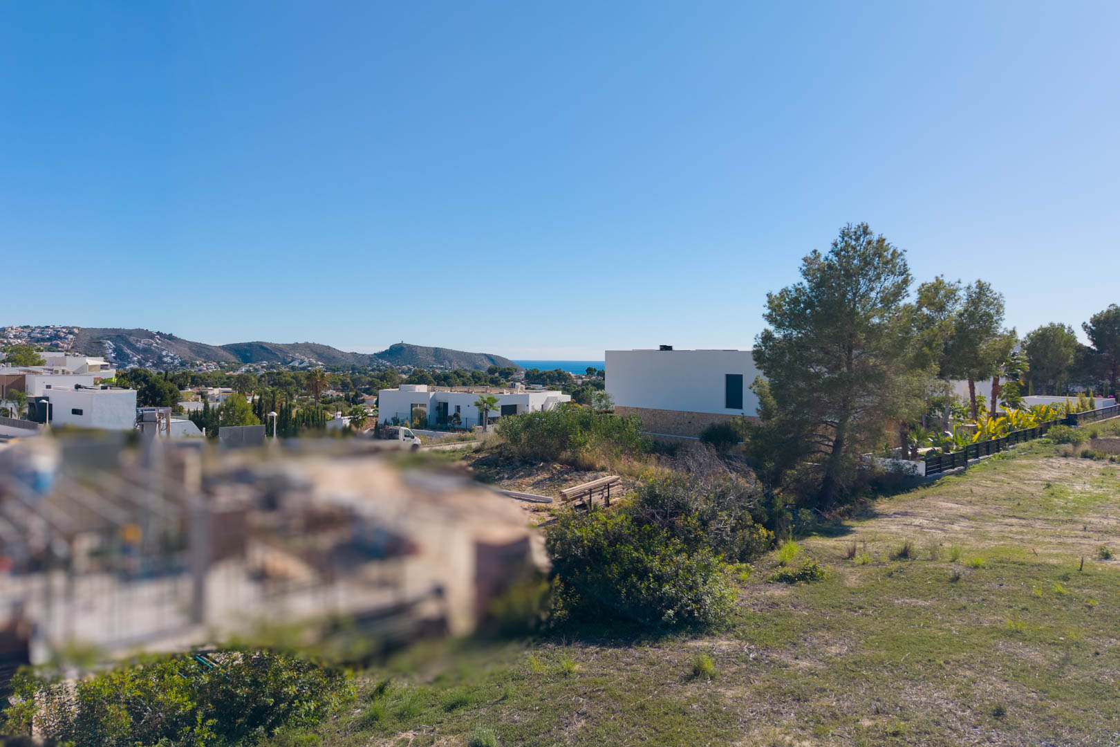 Panoramablick vom Baugrundstück in El Tesoro mit ebenem Gelände, modernen Villen in der Nachbarschaft und freier Sicht auf das Tal und das Mittelmeer.