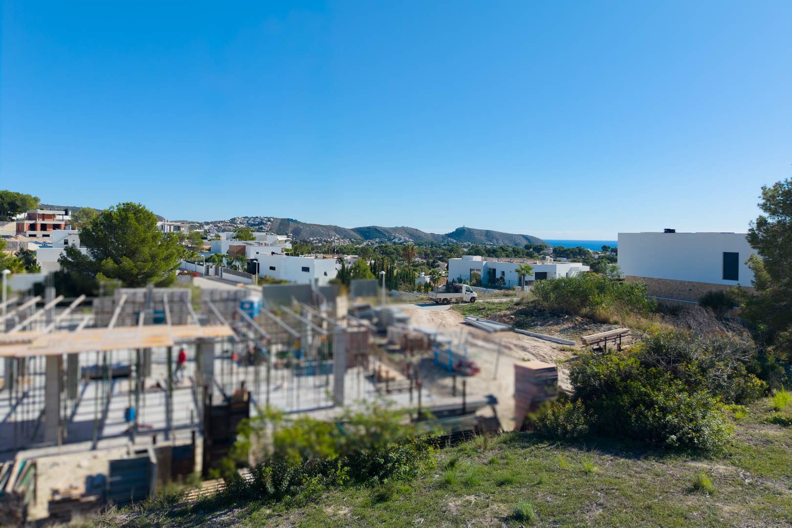 Panoramablick vom Grundstück in El Tesoro mit moderner Architektur, Blick über das Tal und einem Streifen des Mittelmeers am Horizont.