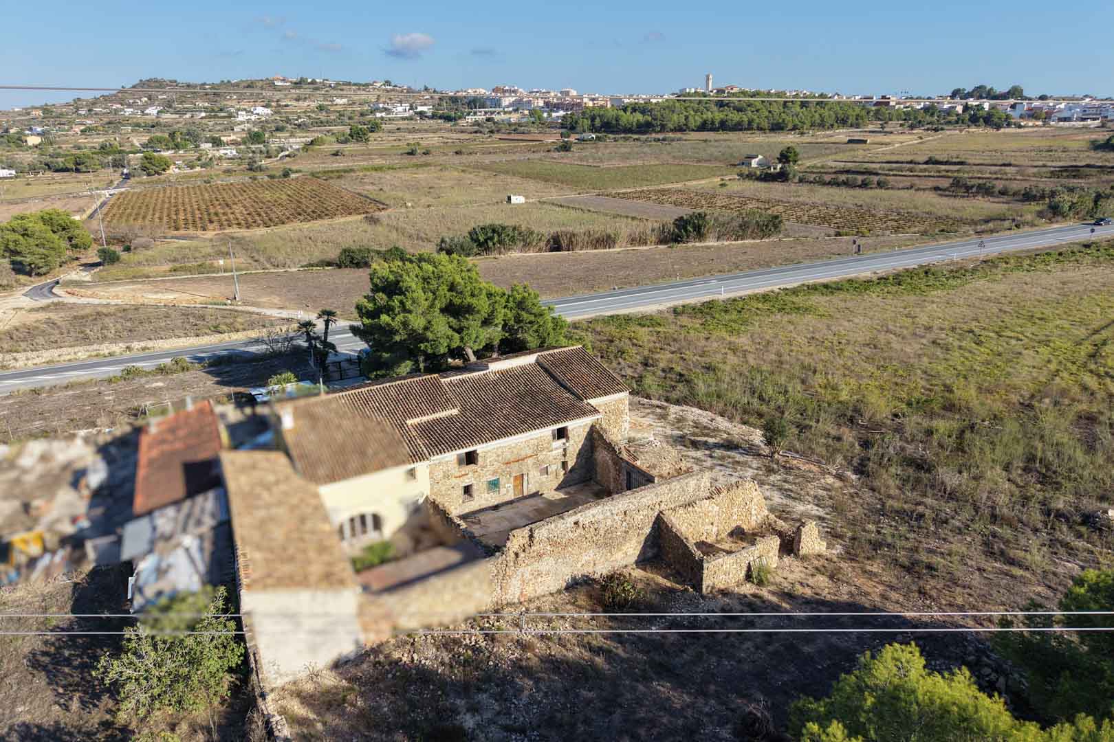 Luftaufnahme des traditionellen Natursteinhauses mit Nebengebäuden auf einem weitläufigen ländlichen Grundstück mit Blick auf Teulada.