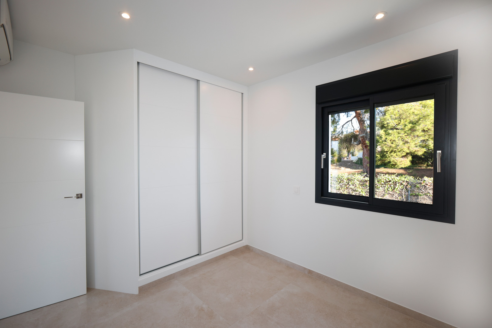 Modernes Schlafzimmer mit weißem Einbauschrank mit Schiebetüren, Feinsteinzeugboden und schwarzem Aluminiumfenster mit Blick in den Garten.
