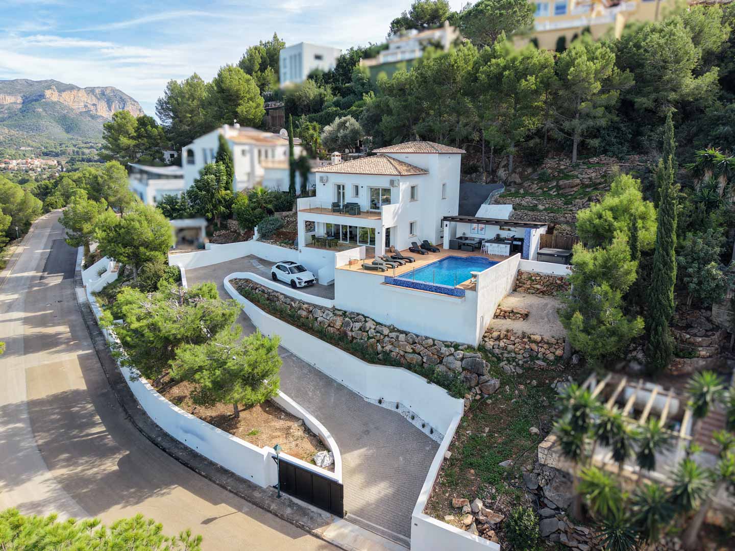 Luftaufnahme der mediterranen Villa mit privatem Pool, mehreren Terrassenebenen und Außenküche, eingebettet in ein Hanggrundstück mit Natursteinmauern.