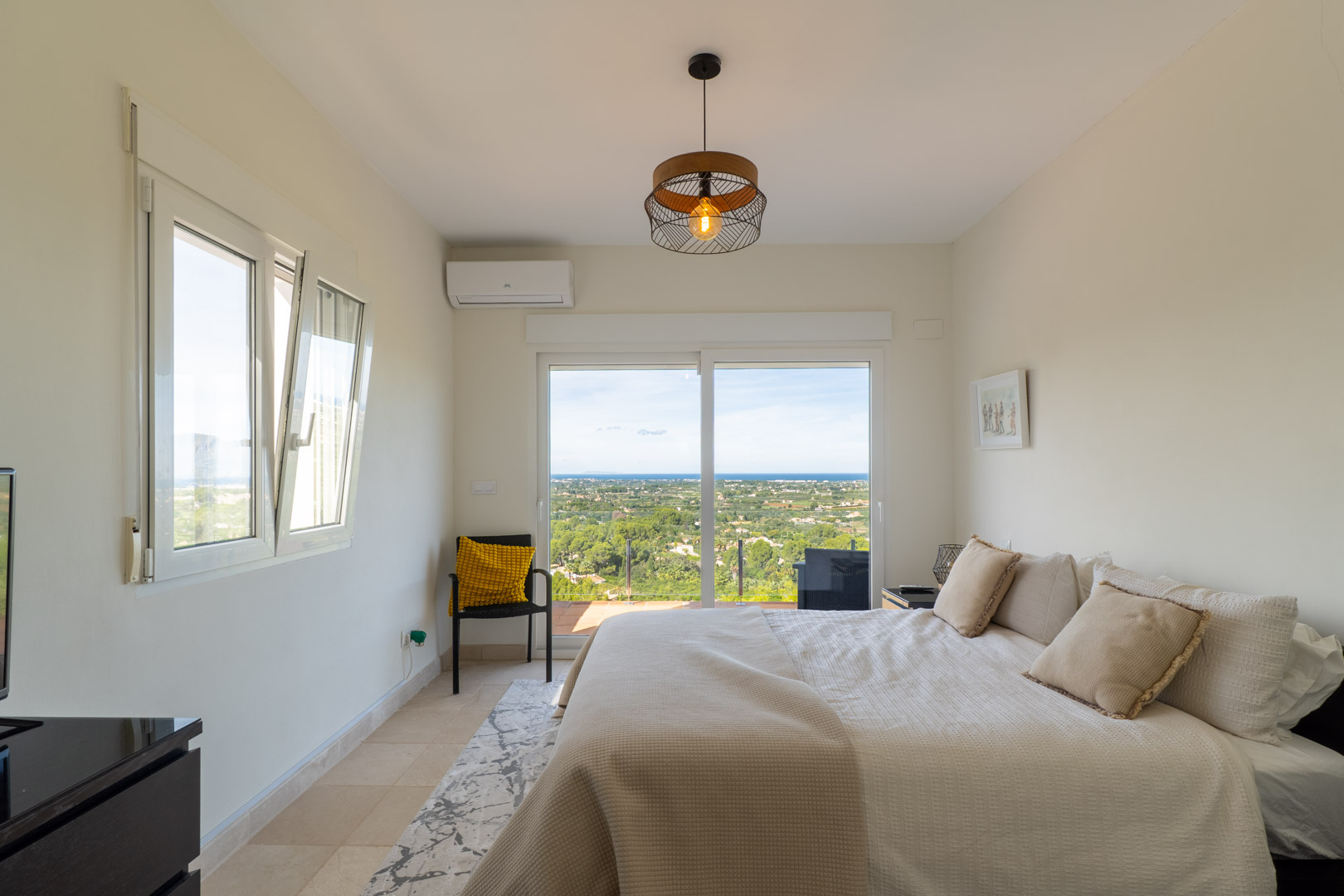 Schlafzimmer mit Terrassenzugang und Panoramablick auf das Meer. Mit Klimaanlage, Fliesenboden und einer großen Glasschiebetür für viel Tageslicht.