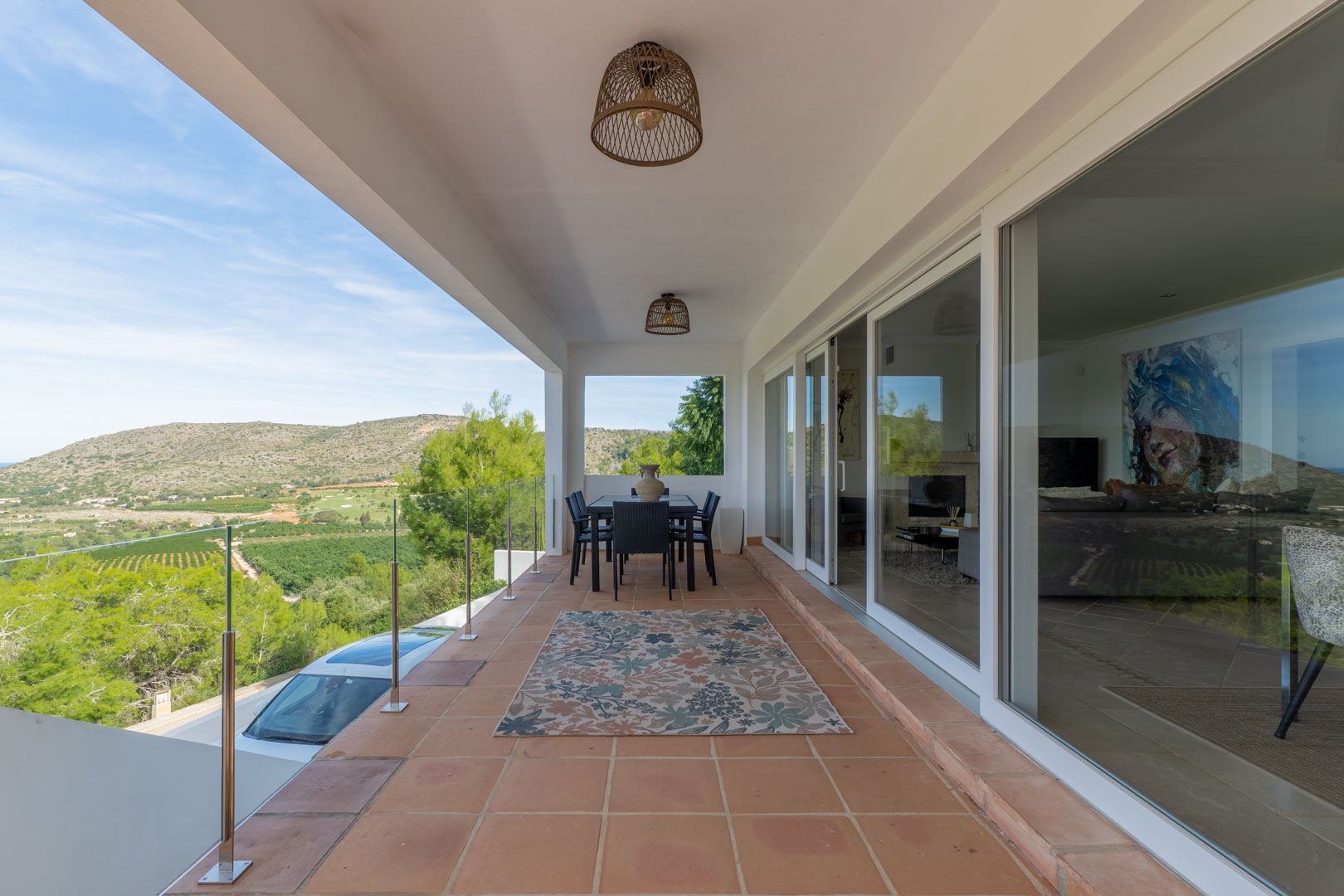 Überdachte Terrasse mit Terrakottaboden, Glasgeländer und Panoramablick auf den Golfplatz. Ausgestattet mit Essbereich im Freien und großen Glasschiebetüren zum Wohnbereich.